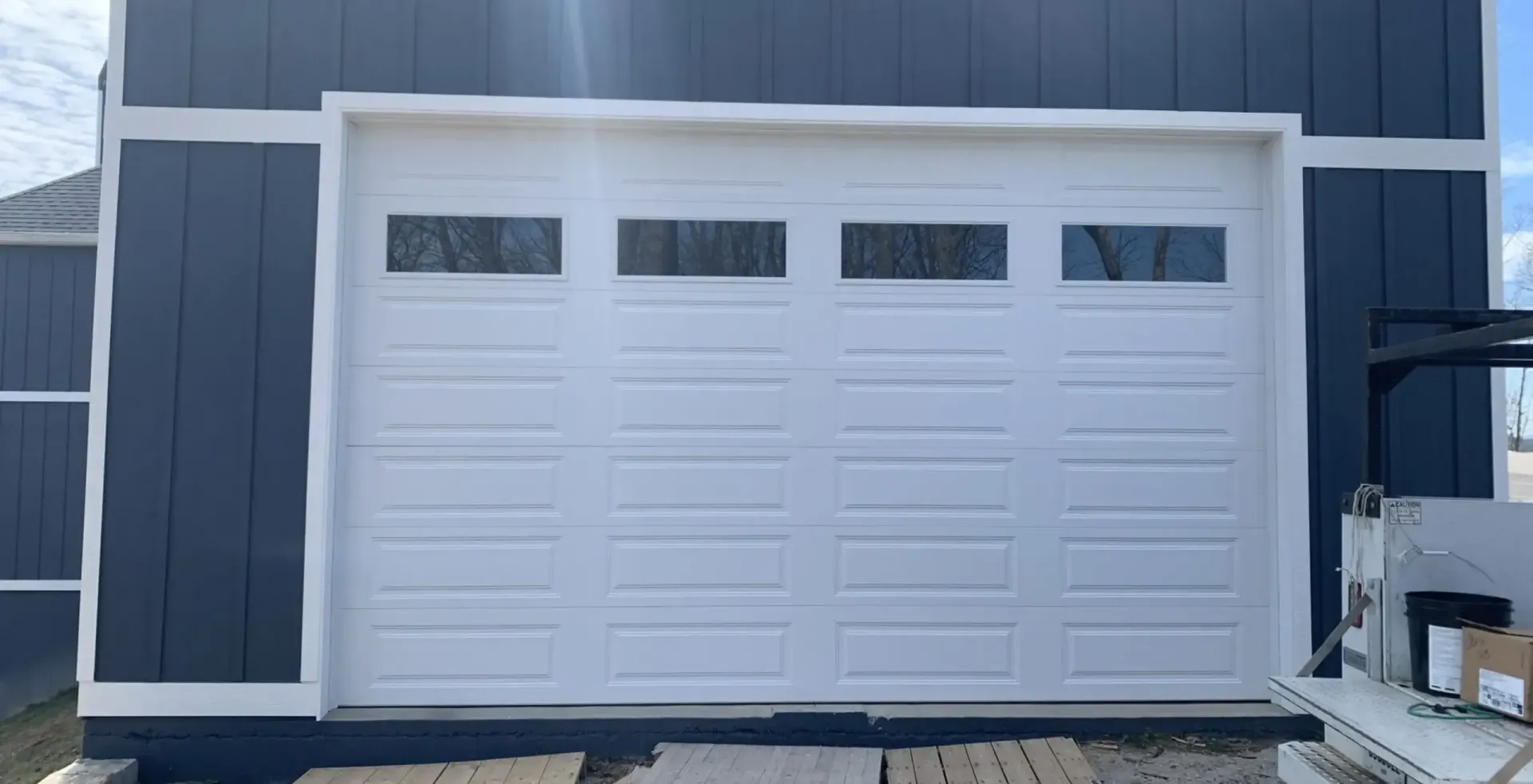 White three-car garage door on a dark gray building exterior