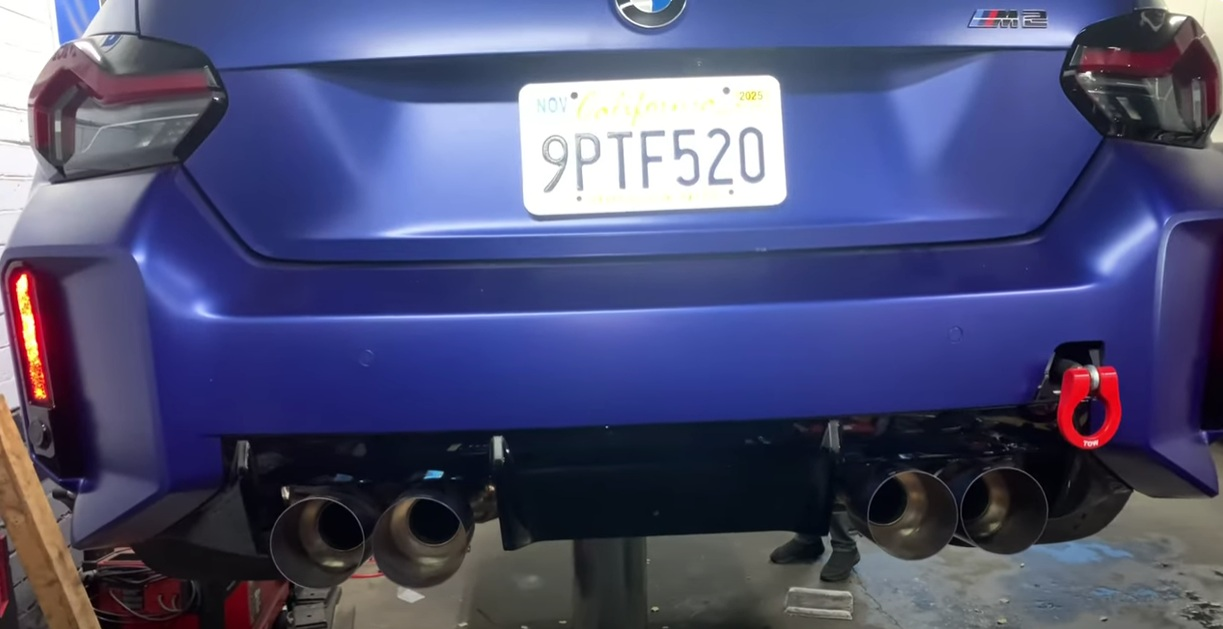 A blue BMW M4 is parked in a garage