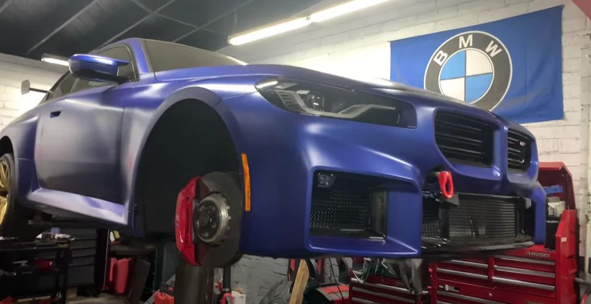 A blue BMW is sitting on a lift in a garage