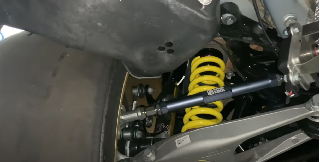 A close up of a car suspension with a yellow spring