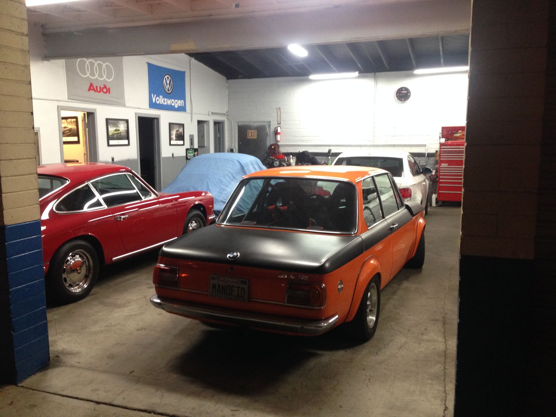 An orange car is parked in a garage with other cars.