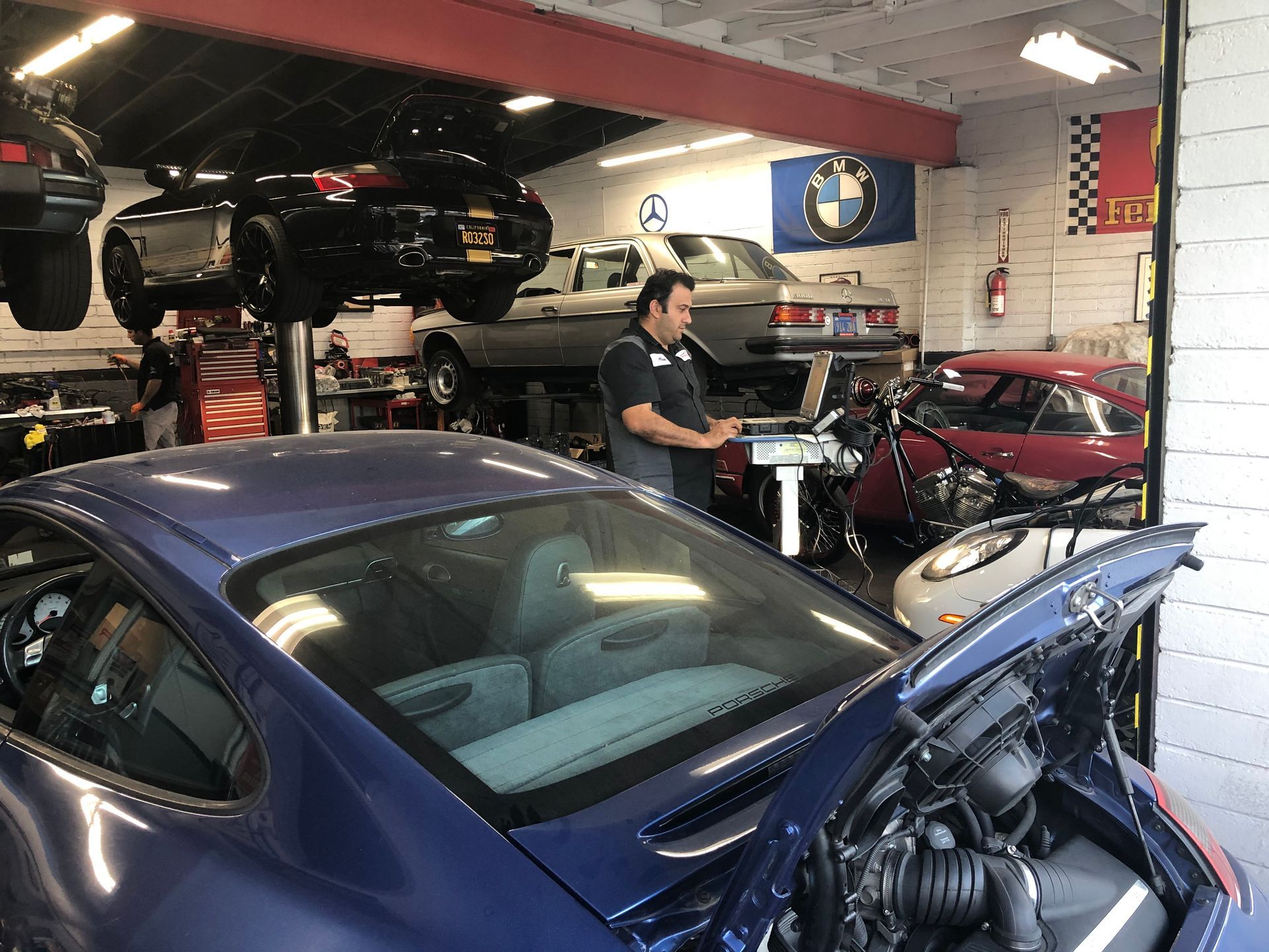 A man is working on a blue car in a garage.