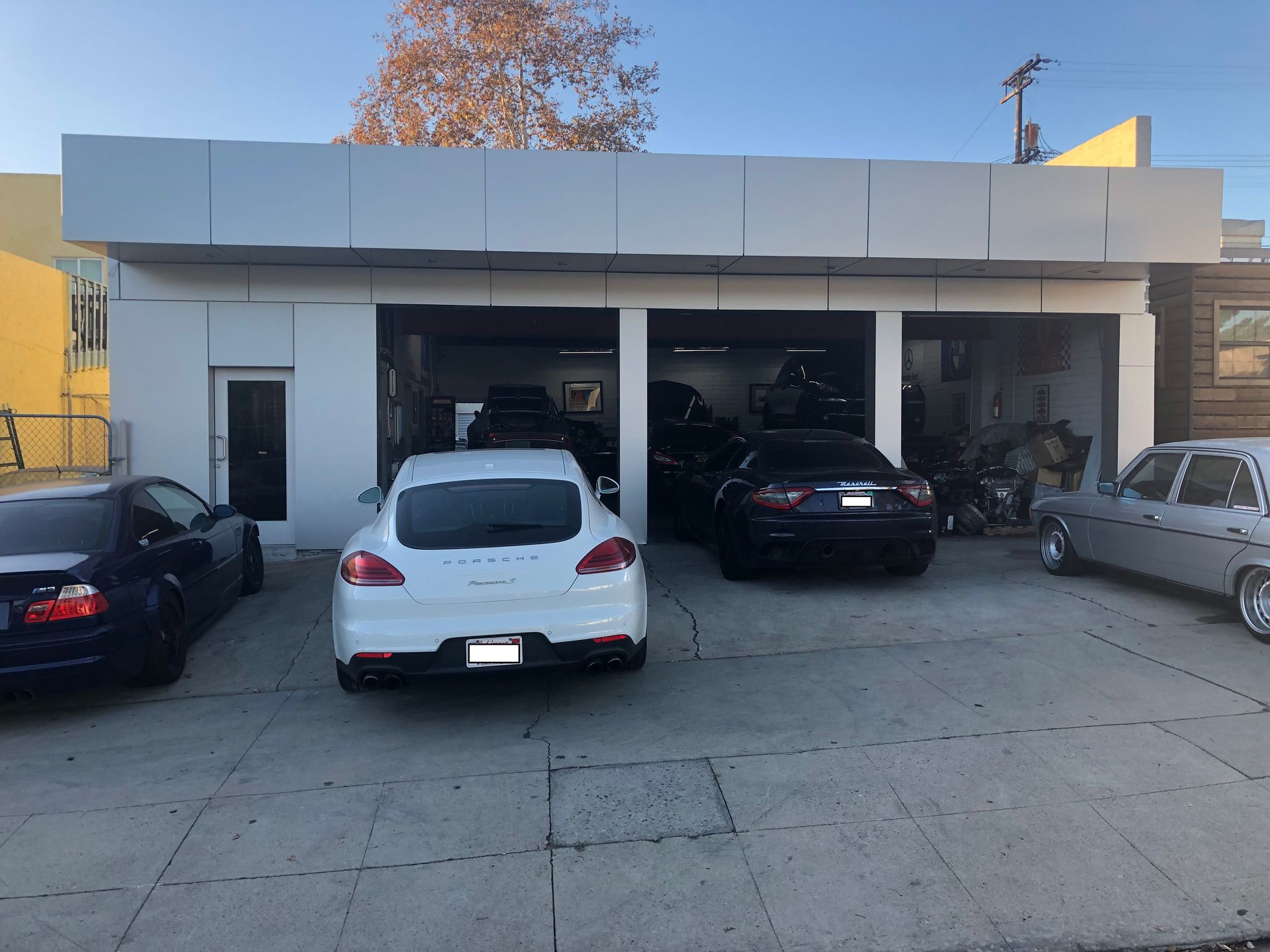 A white car is parked in front of a garage.