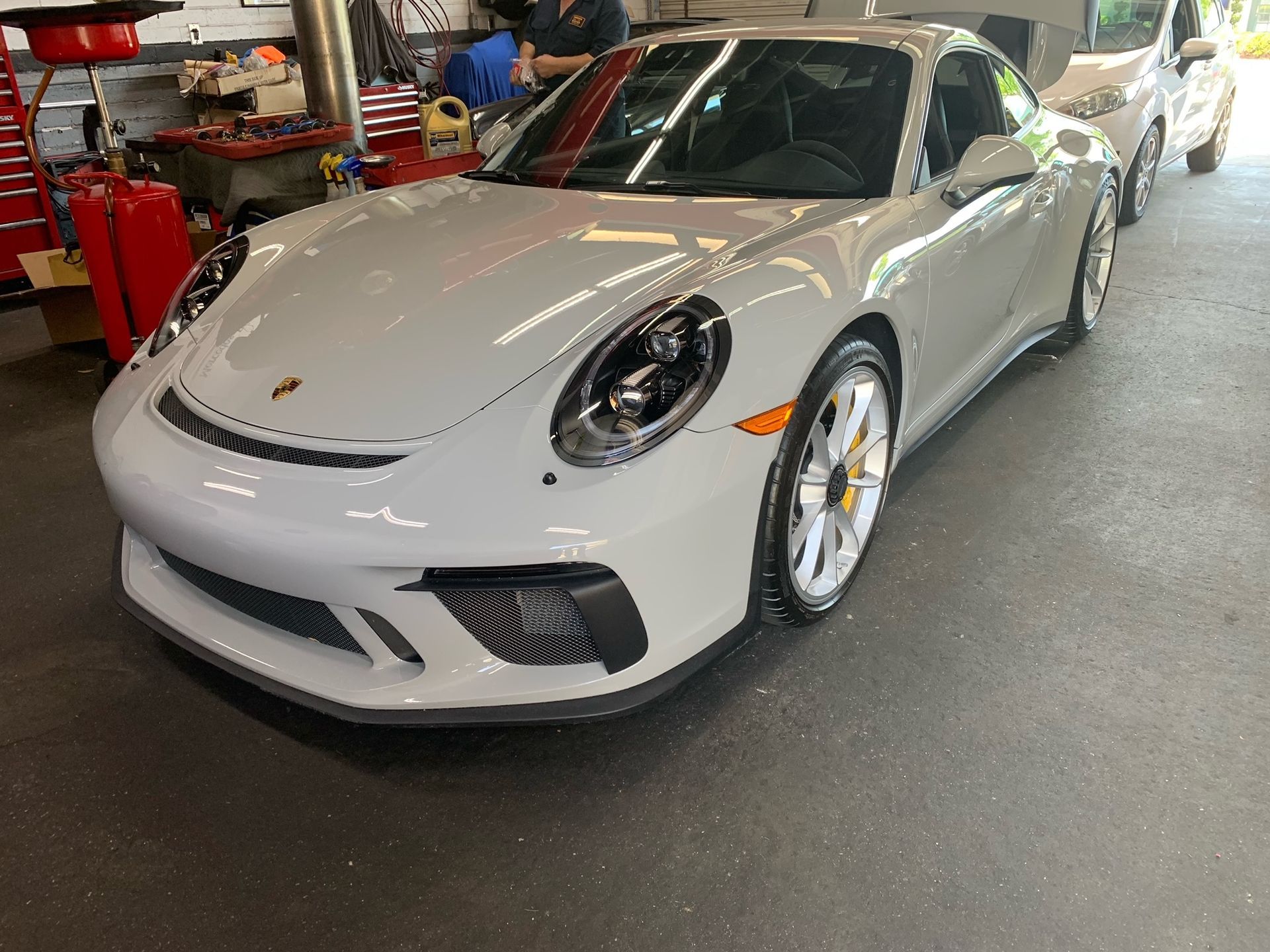 A white Porsche 911 GT3 is parked in a garage.