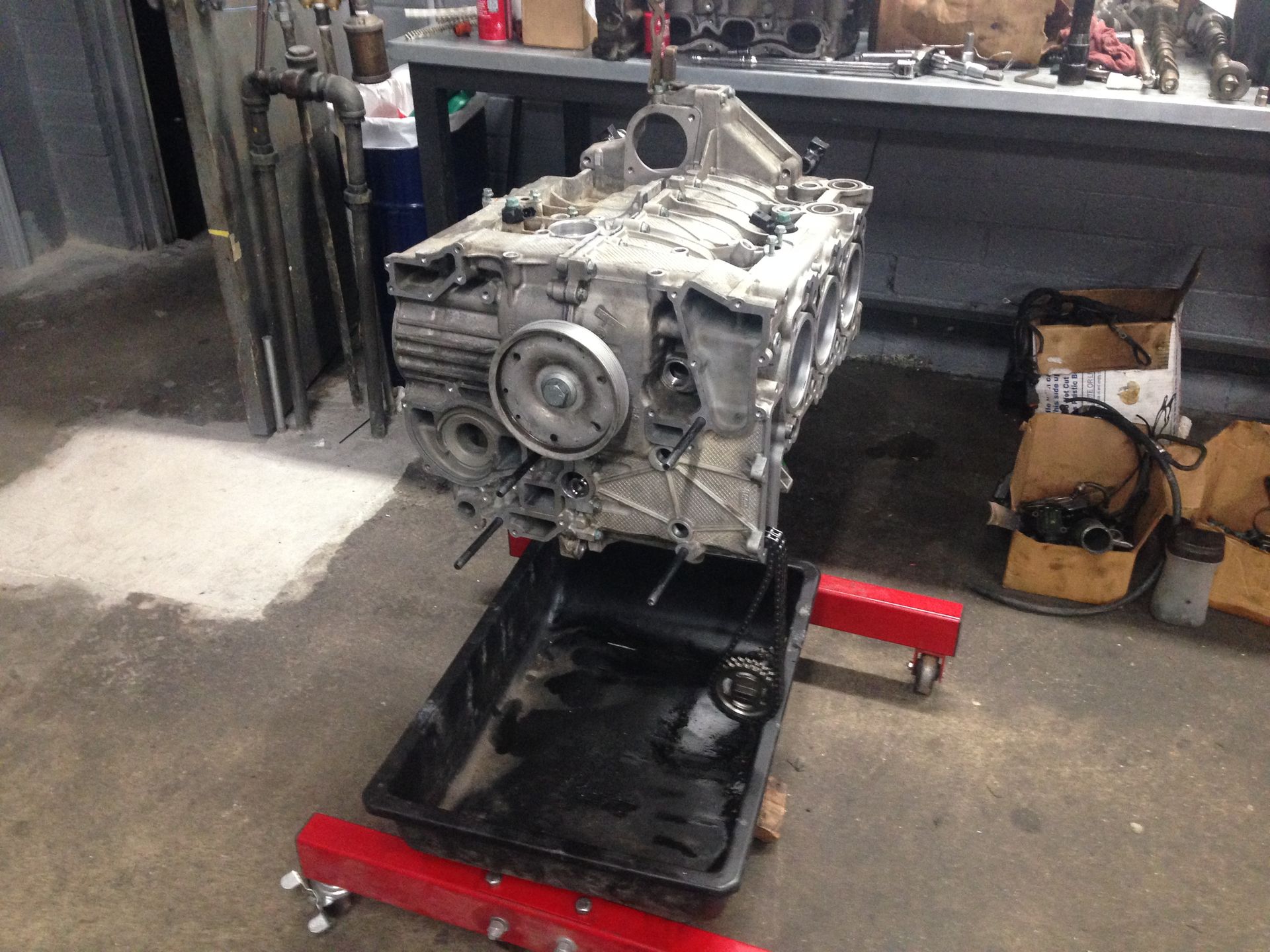 A car engine is sitting on a stand in a garage.