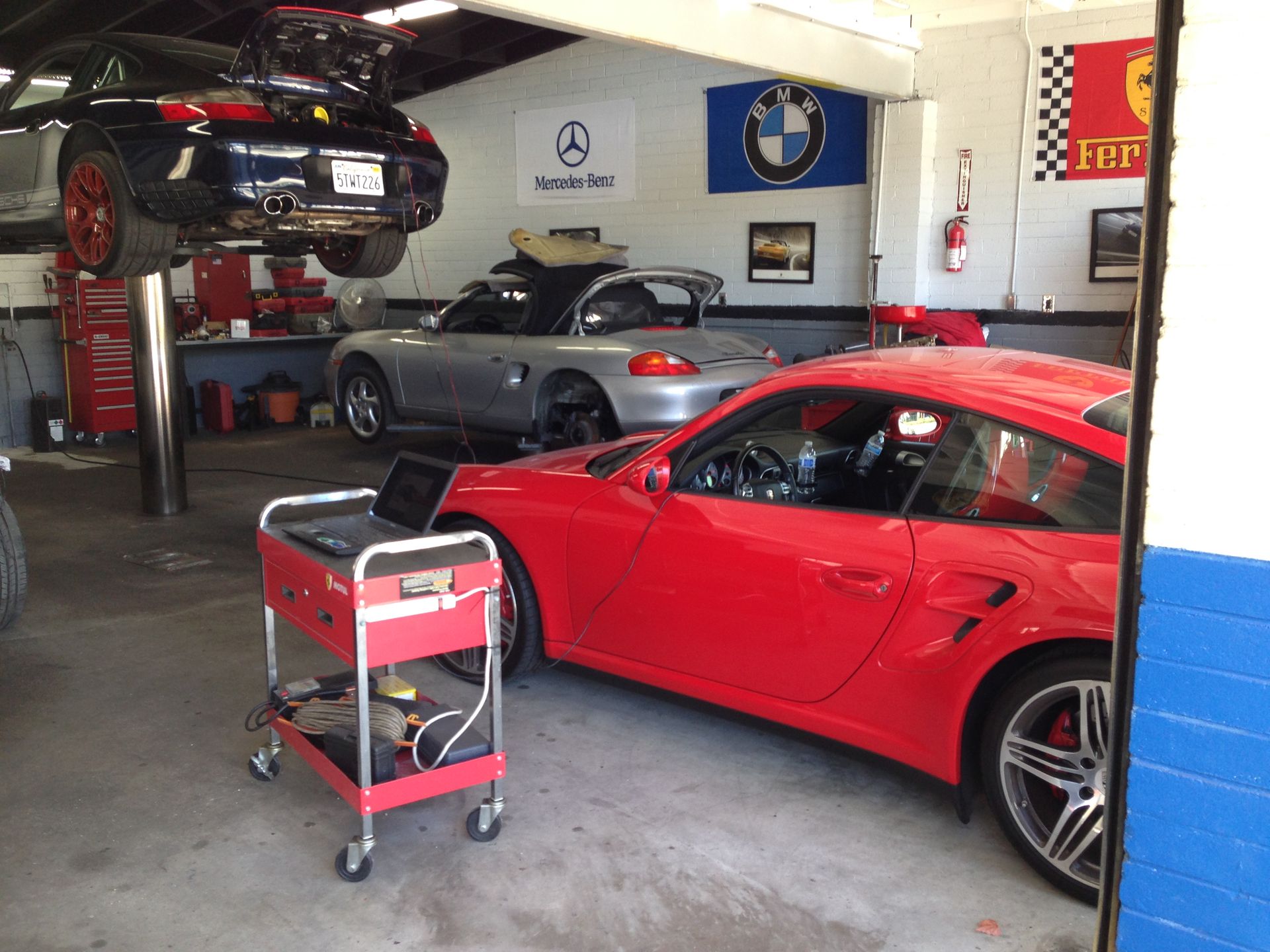 A red car is parked in a garage with other cars.