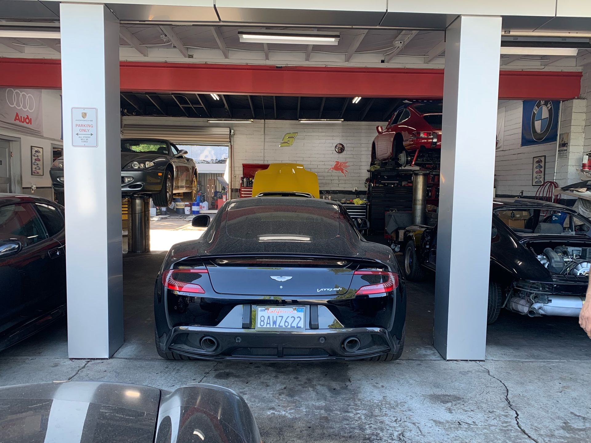 A black sports car is parked in a garage with other cars.