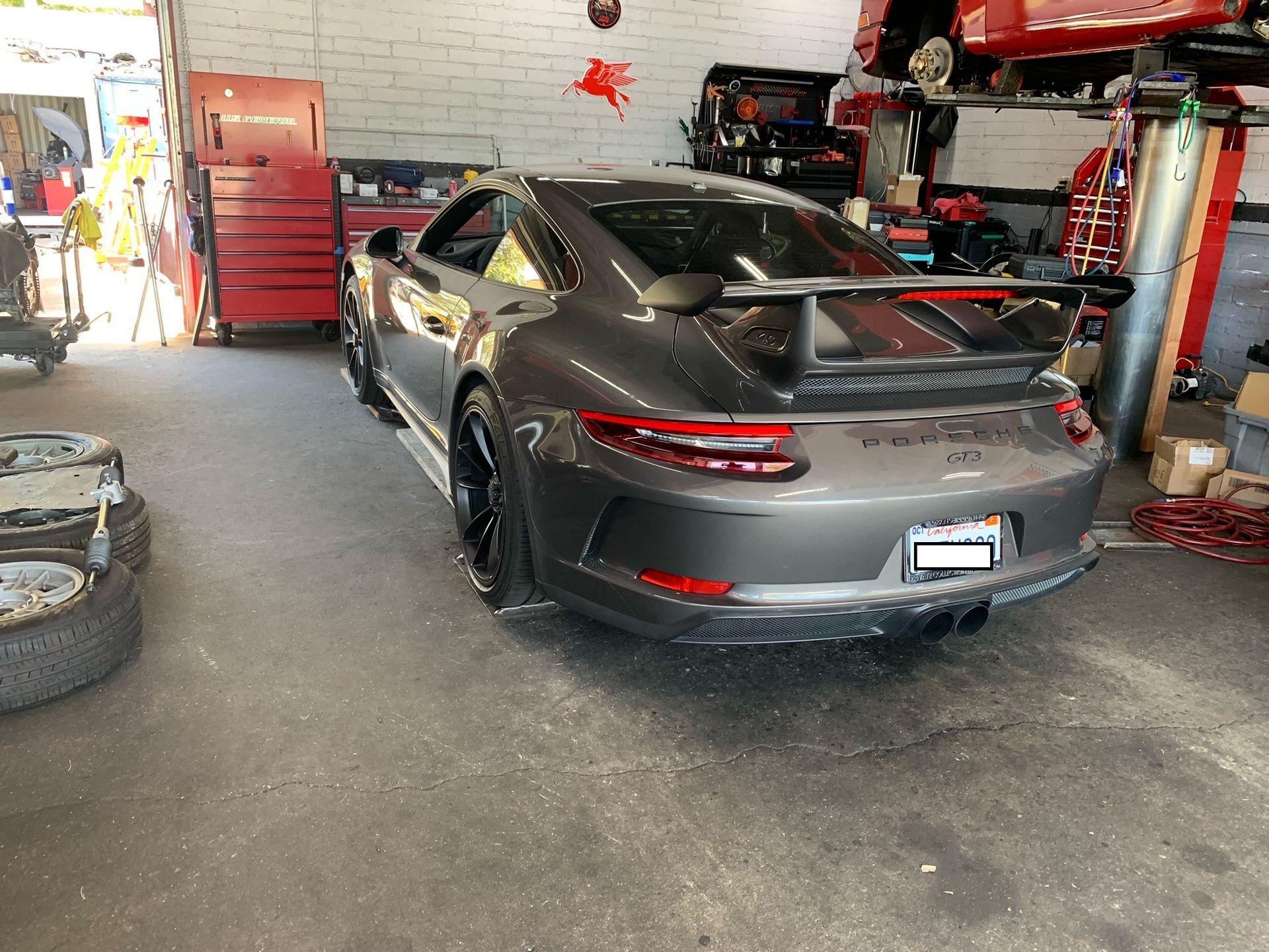 A gray sports car is parked in a garage next to tires.