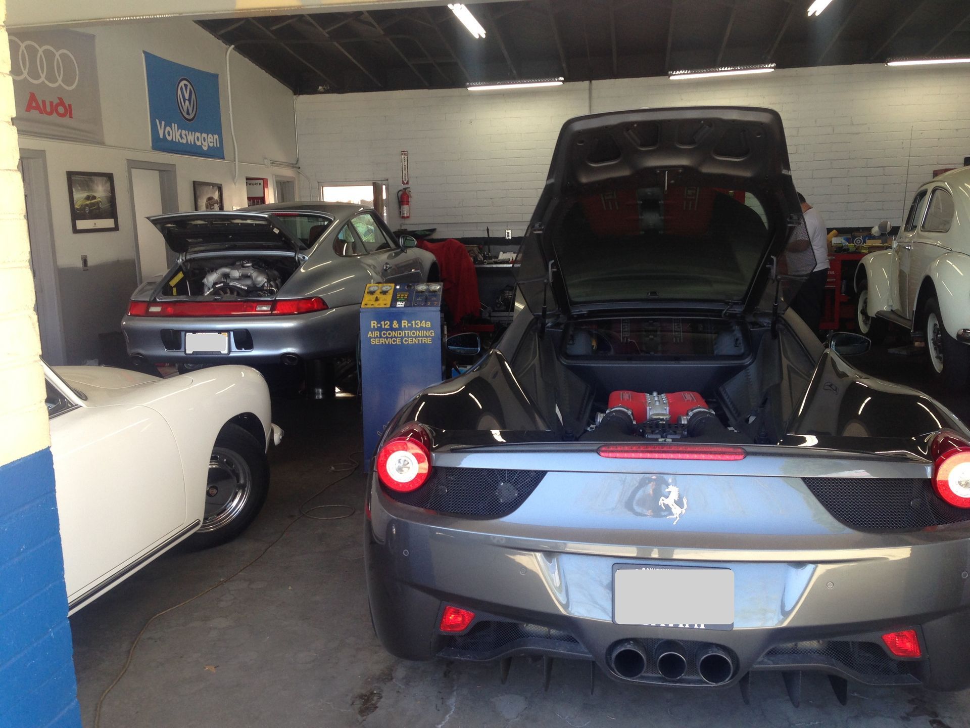 A Ferrari with the hood up in a garage