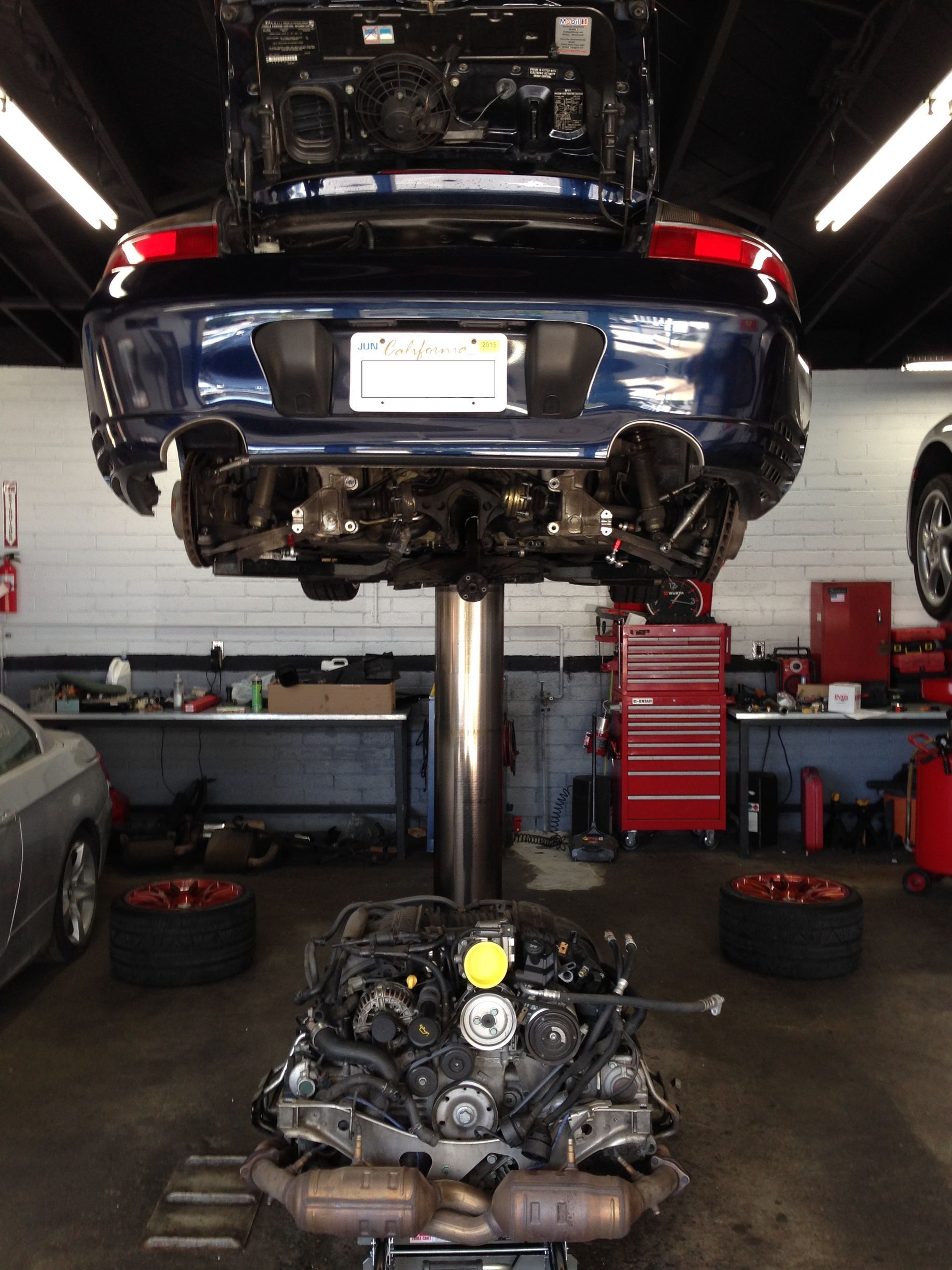 A blue car is sitting on a lift in a garage.