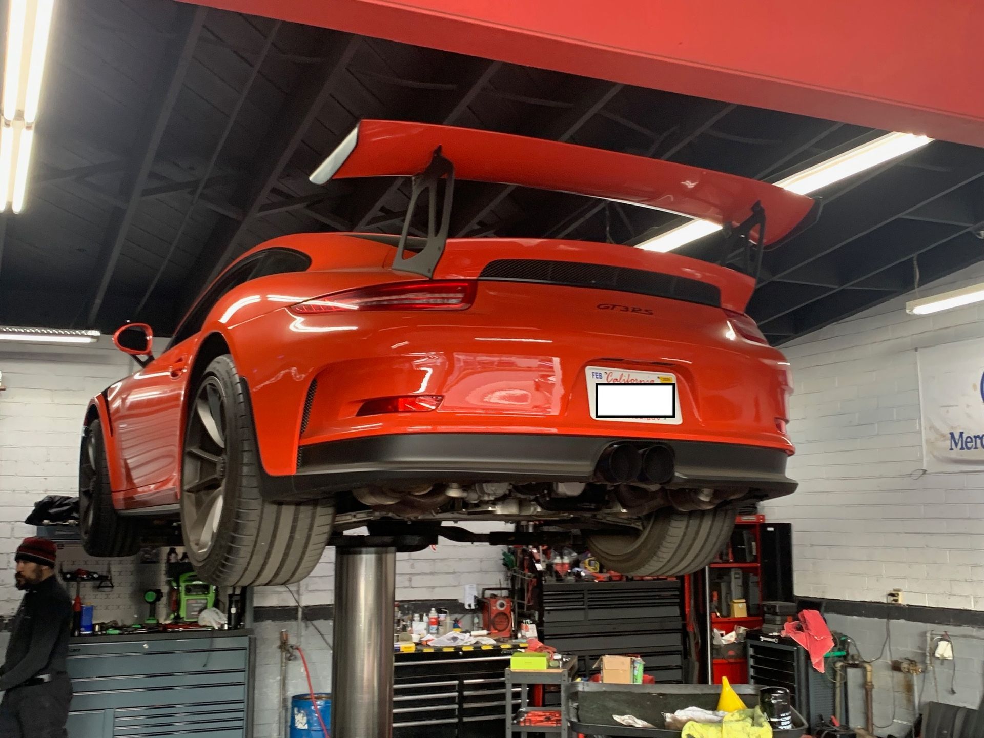 A red Porsche 911 GT3 is sitting on a lift in a garage.