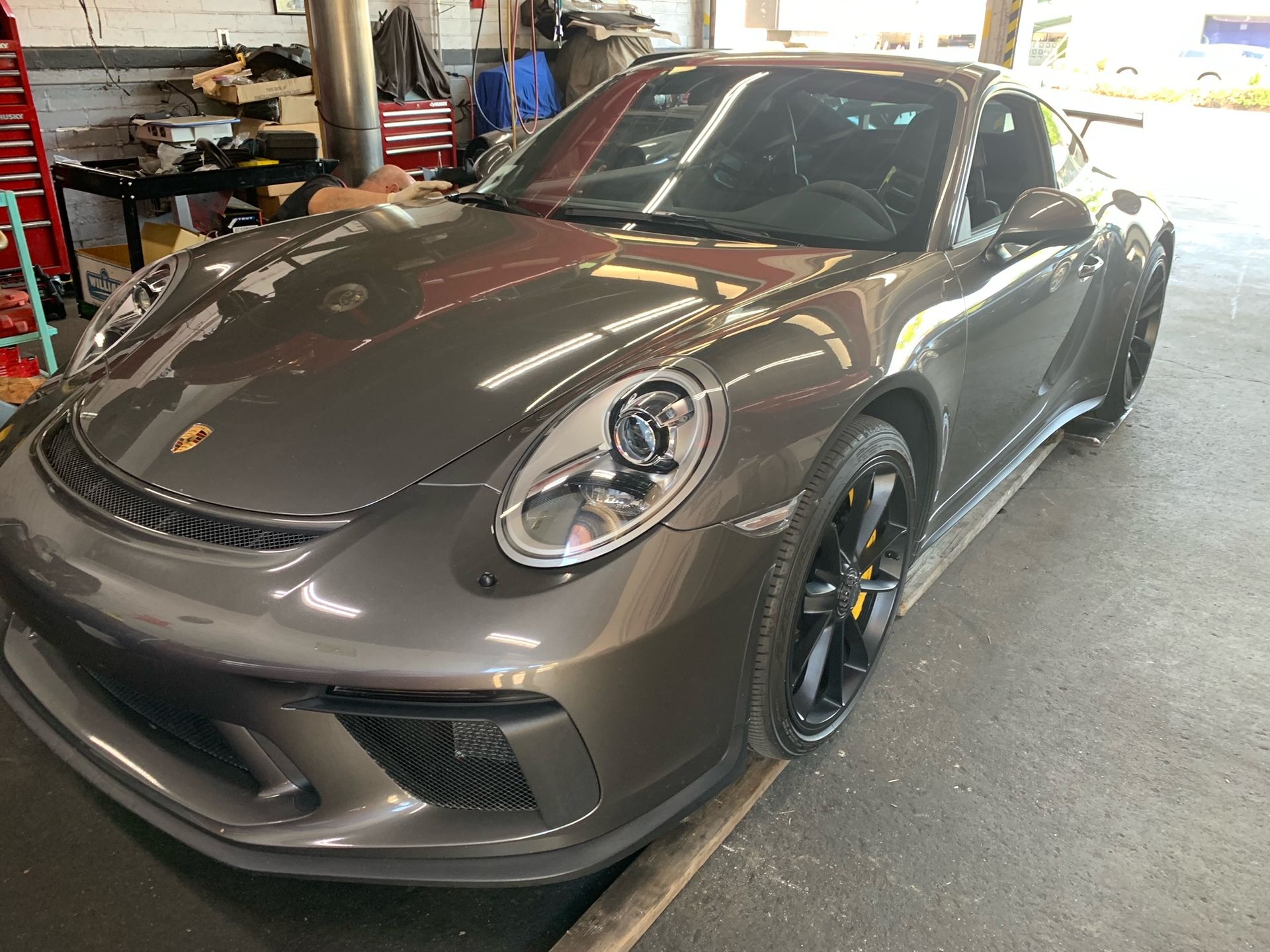 A gray Porsche 911 is parked in a garage.