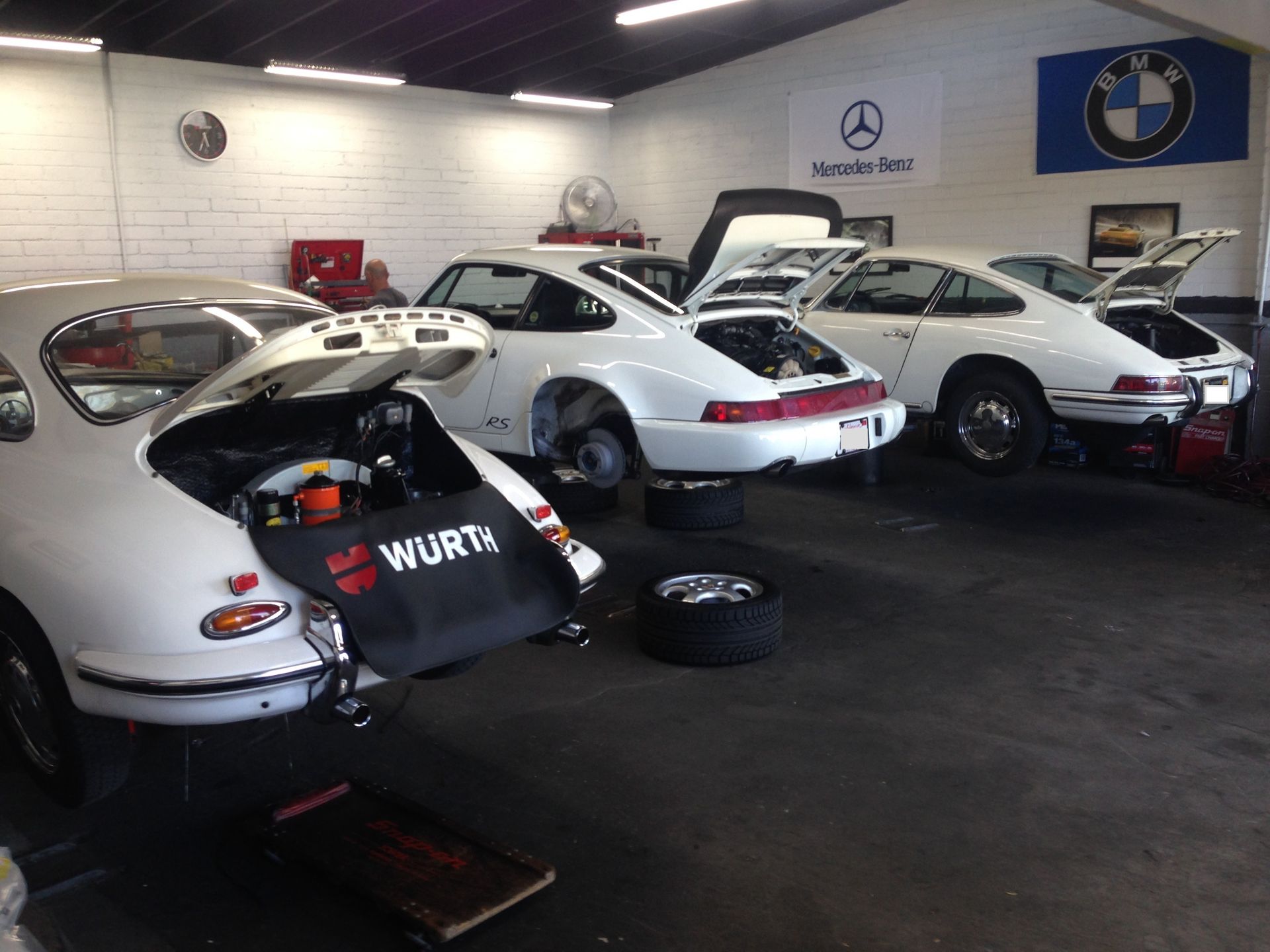 A row of cars are parked in a garage with their hoods open.