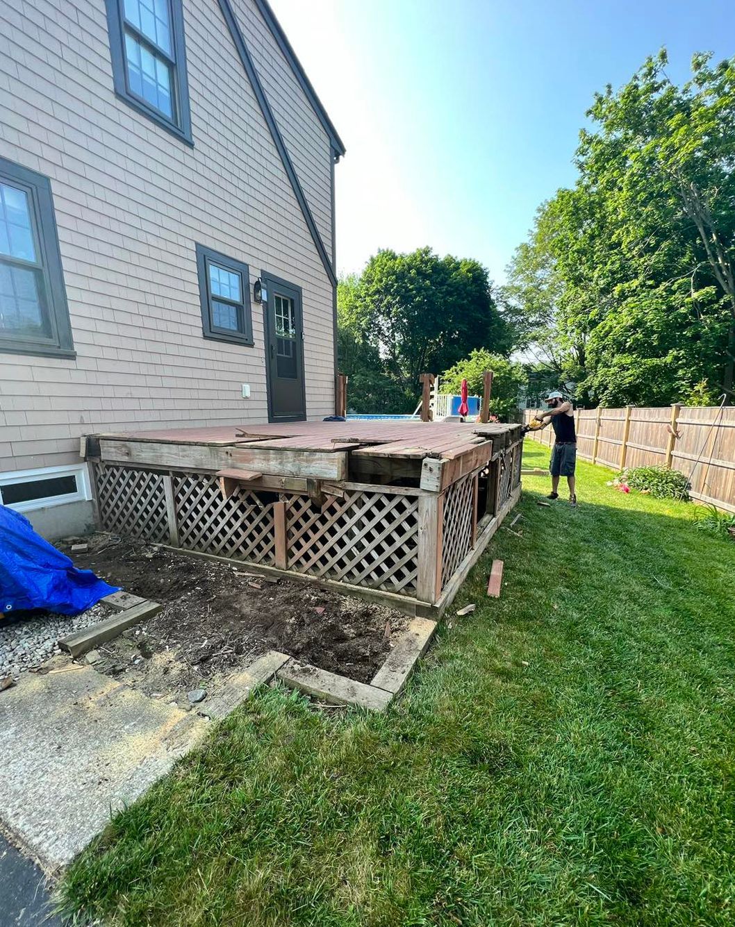 A man is standing in front of a house with a deck being built