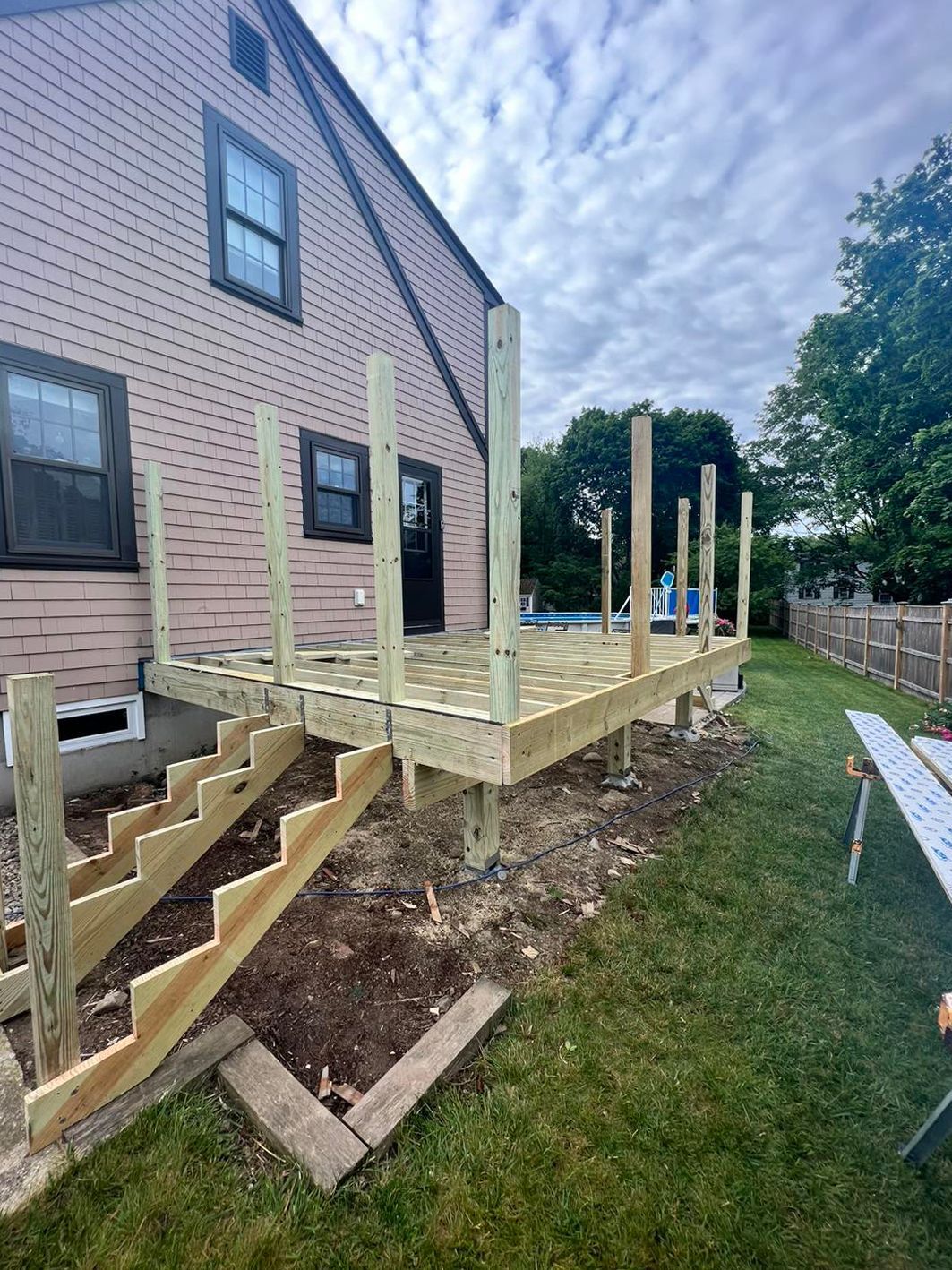 A wooden deck is being built in the backyard of a house