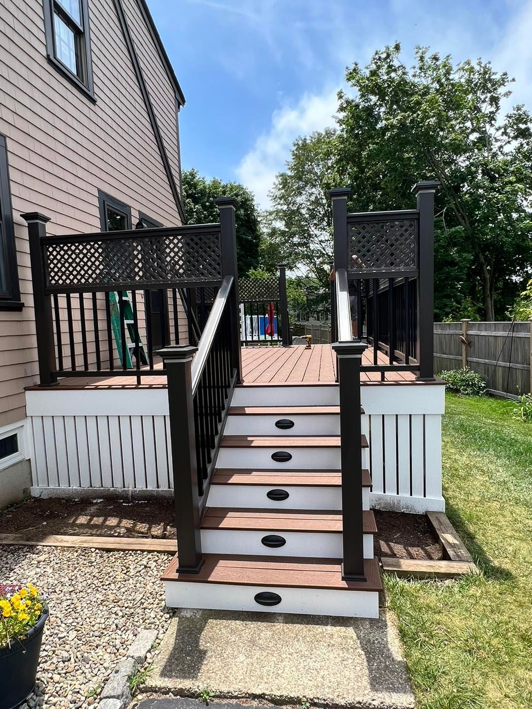 A deck with stairs leading up to it and a house in the background