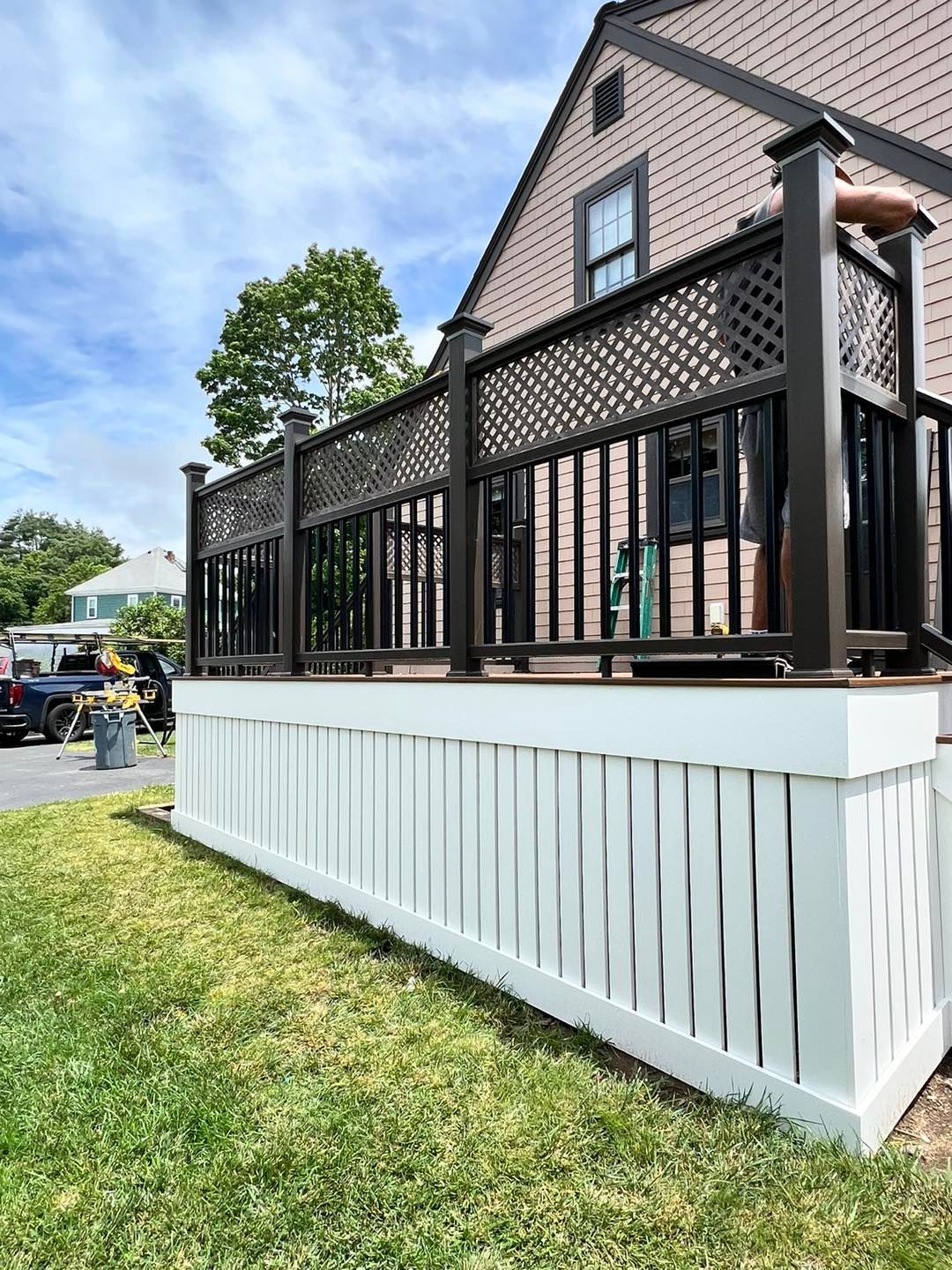 A deck with a black railing and a white fence in front of a house