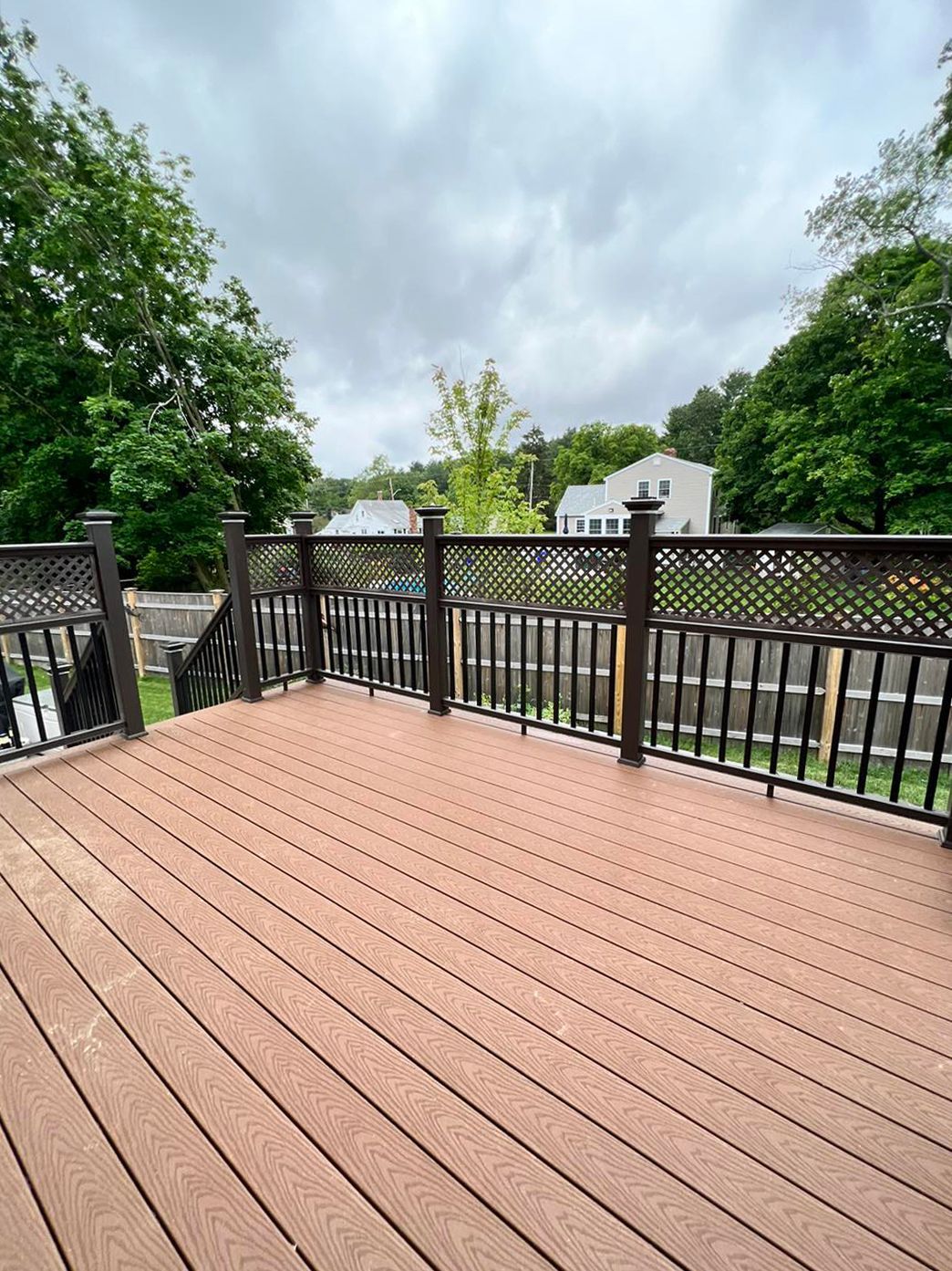 A wooden deck with a metal railing and stairs leading up to it
