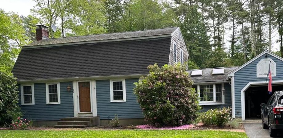 A blue house with a garage and a car parked in front of it