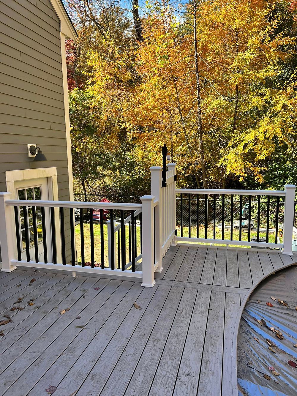 A wooden deck with a white railing next to a pool