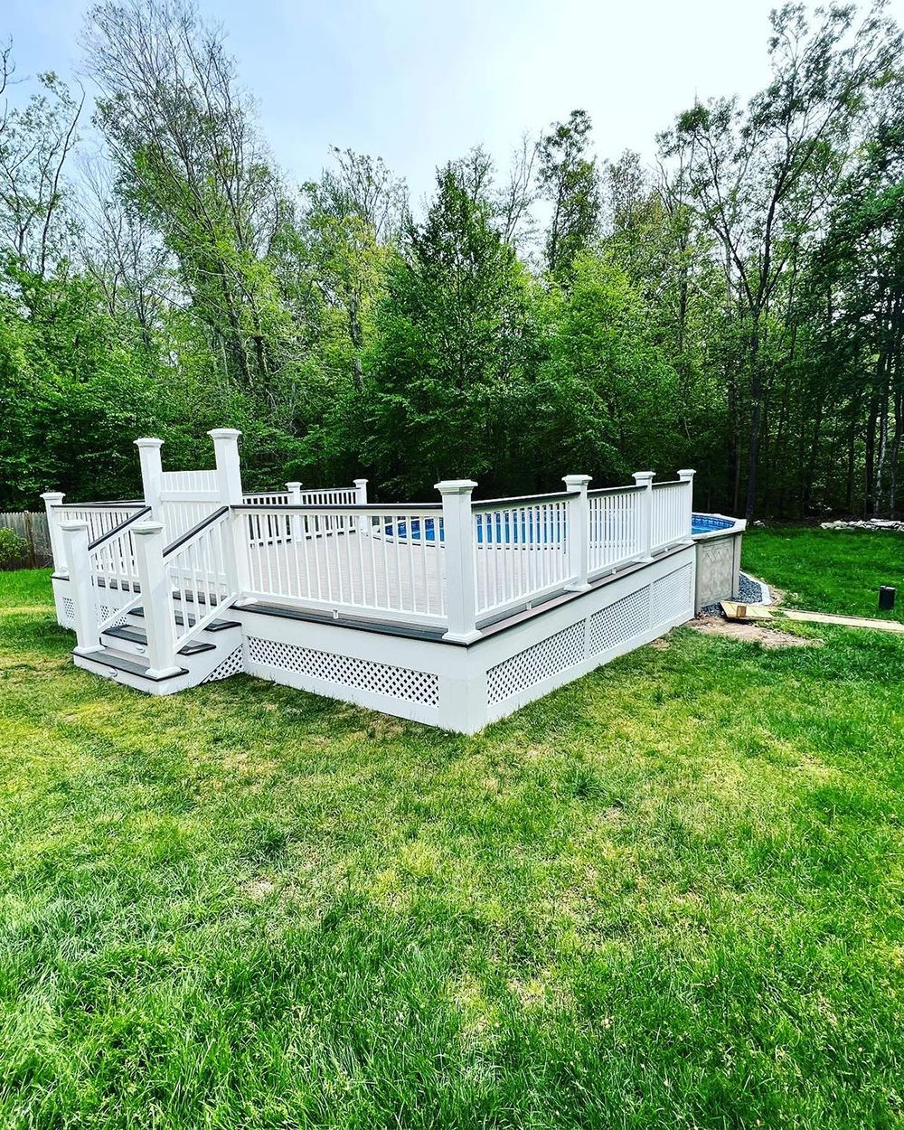 A white deck with stairs and a pool in the backyard