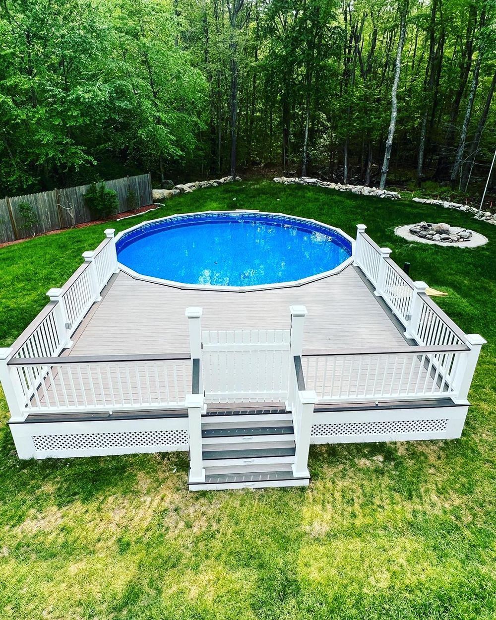 A swimming pool with a deck and stairs in a backyard
