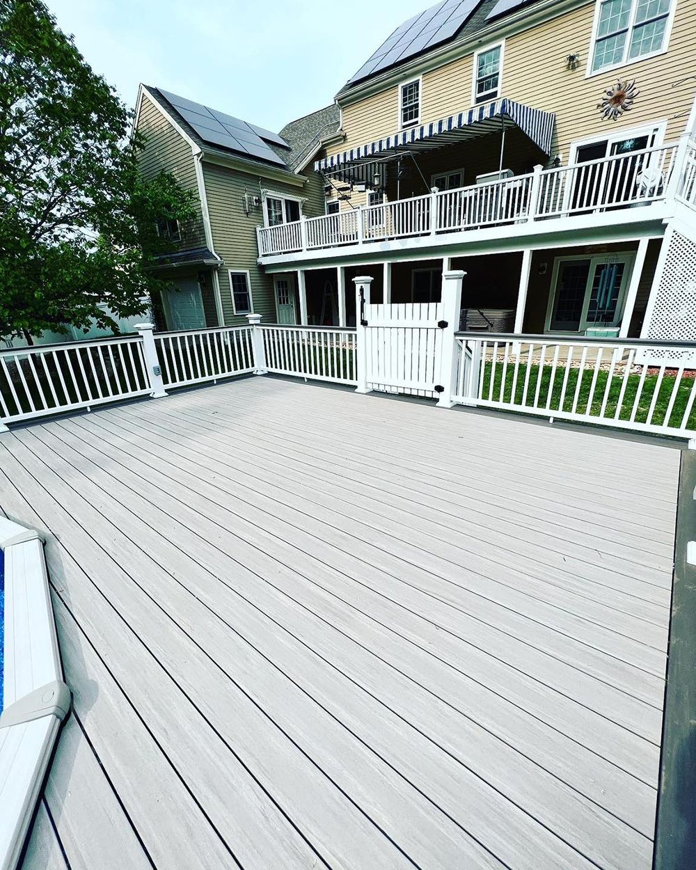A large deck with a white railing and a house in the background