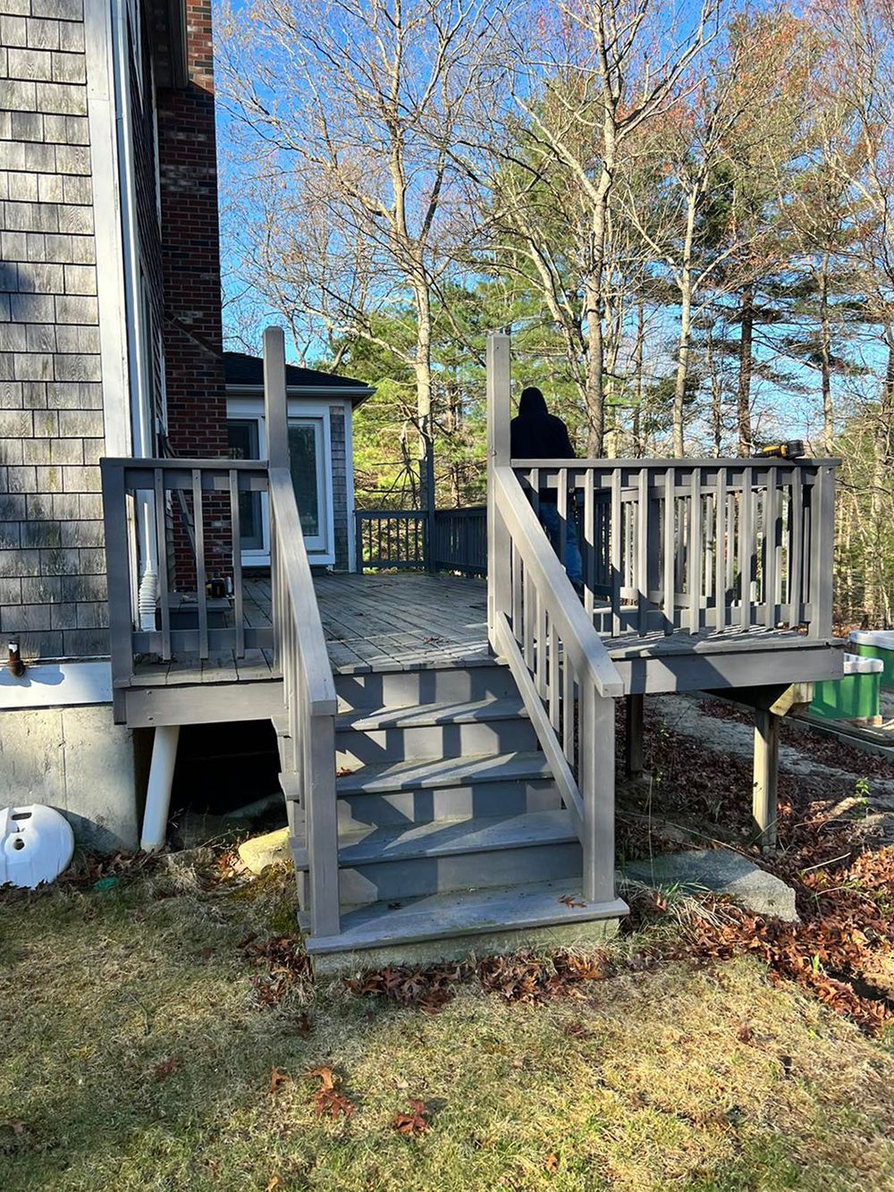 A wooden deck with stairs leading up to it in front of a house