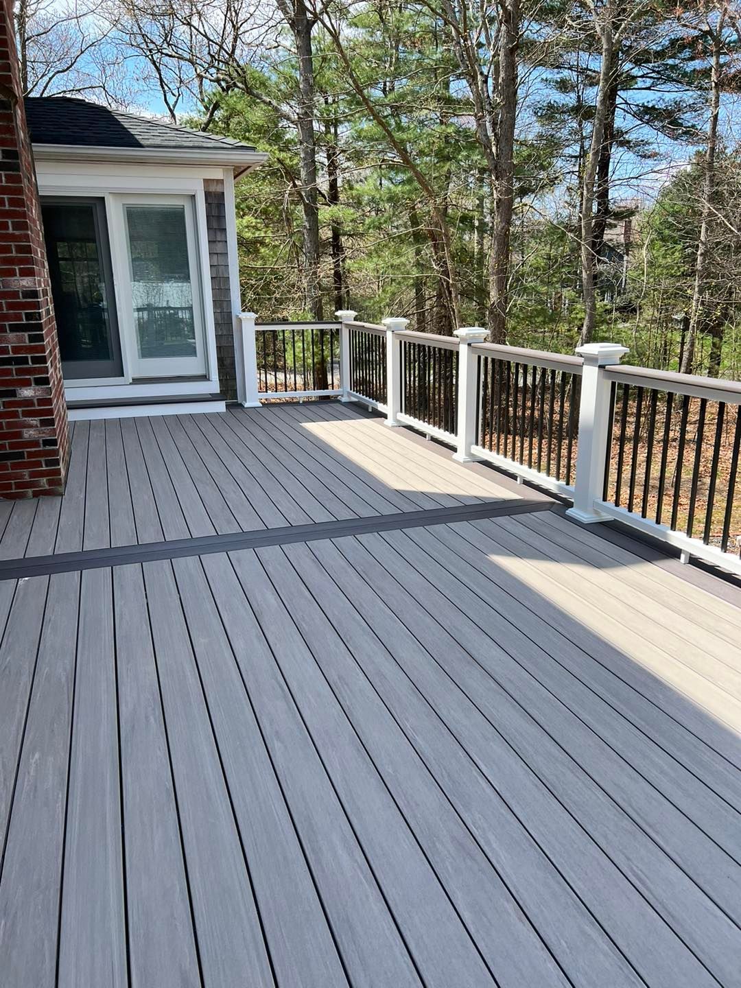 A large deck with a white railing and trees in the background