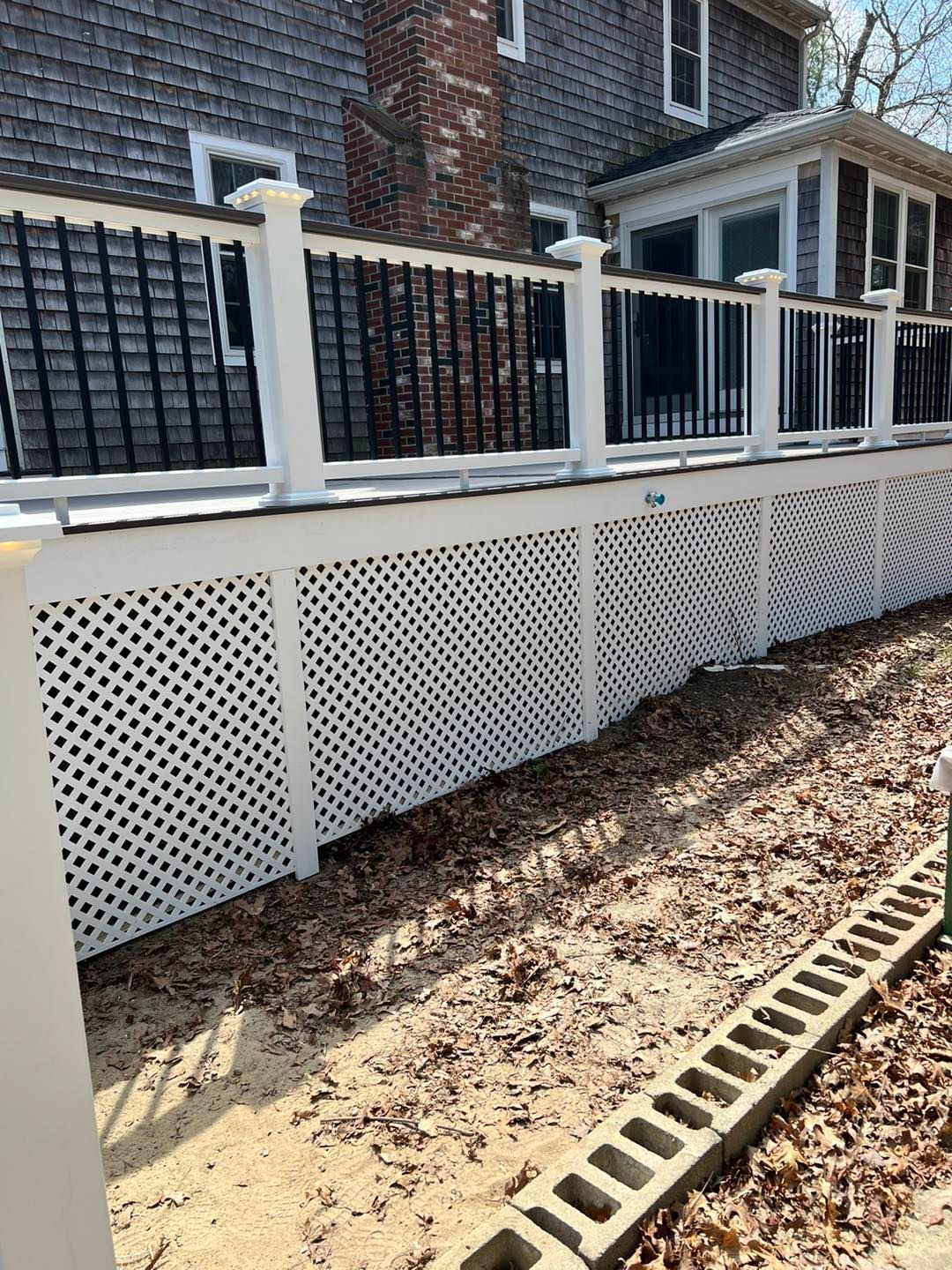 A white fence with a black railing is in front of a house
