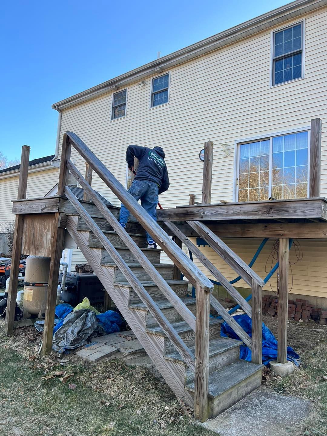 A man is standing on a wooden deck next to a house