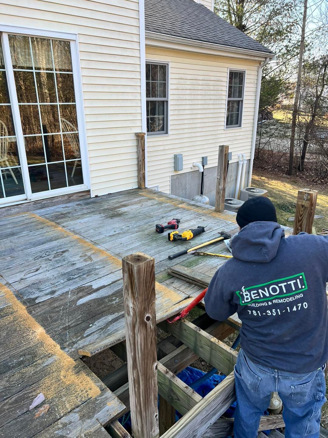 A man is working on a wooden deck in front of a house