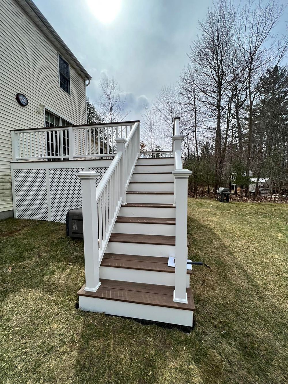 A deck with stairs leading up to it and a house in the background