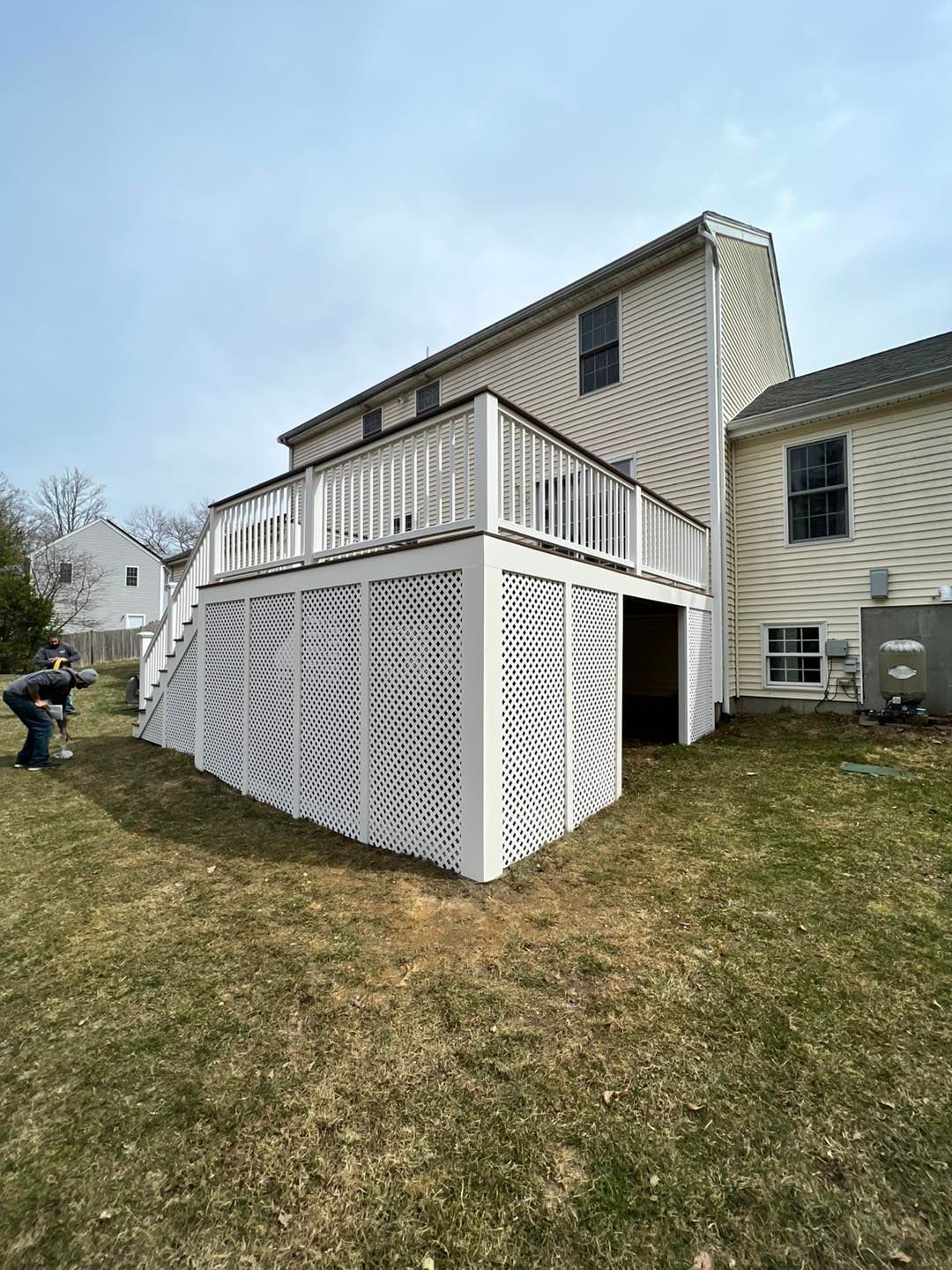 A white deck with stairs is in the backyard of a house