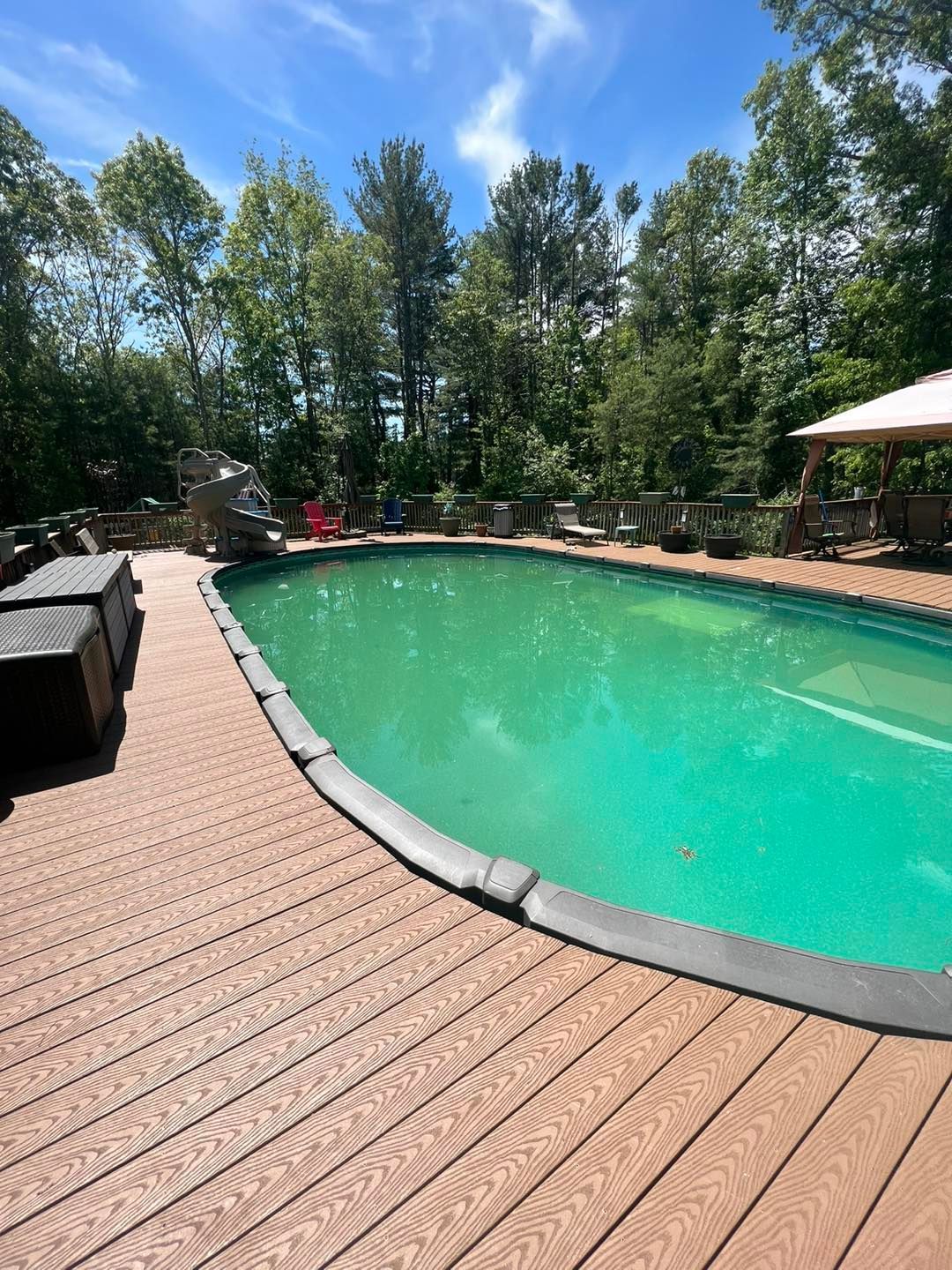 A large swimming pool surrounded by trees and a wooden deck