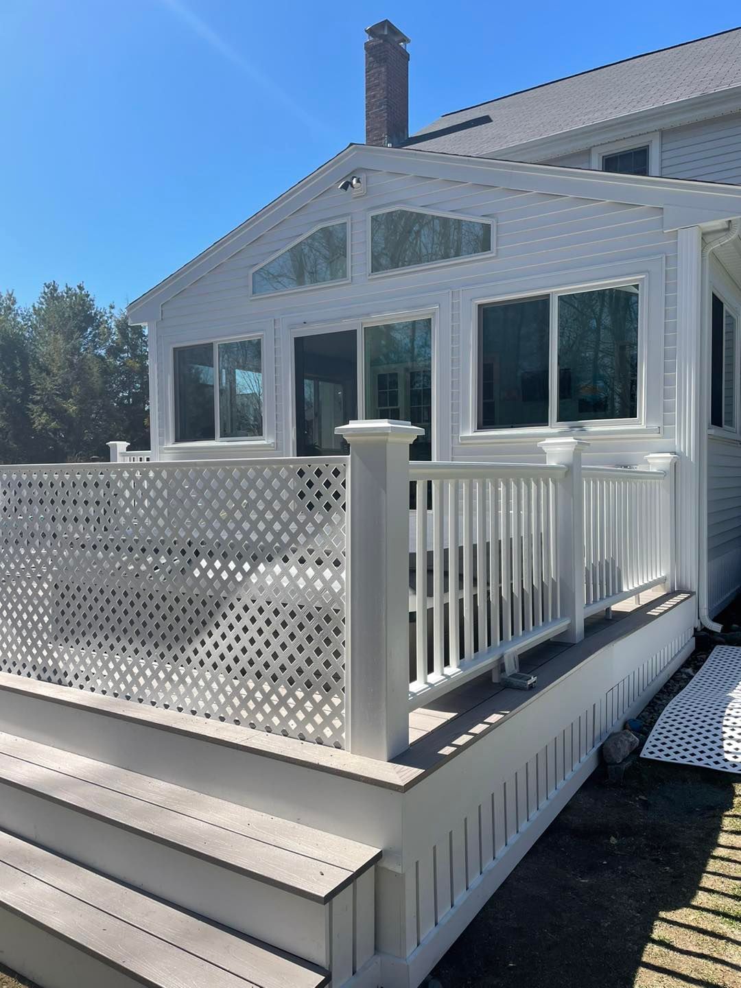 A white house with a white deck and stairs