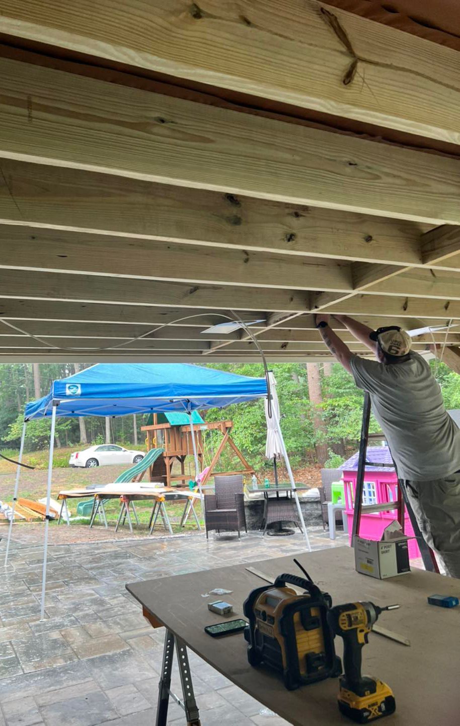 A man is working on a wooden deck under a canopy