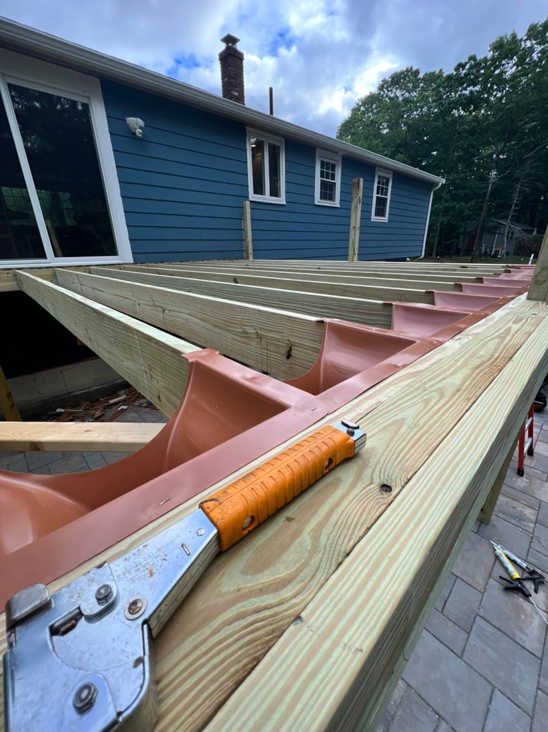 A wooden deck is being built in front of a blue house
