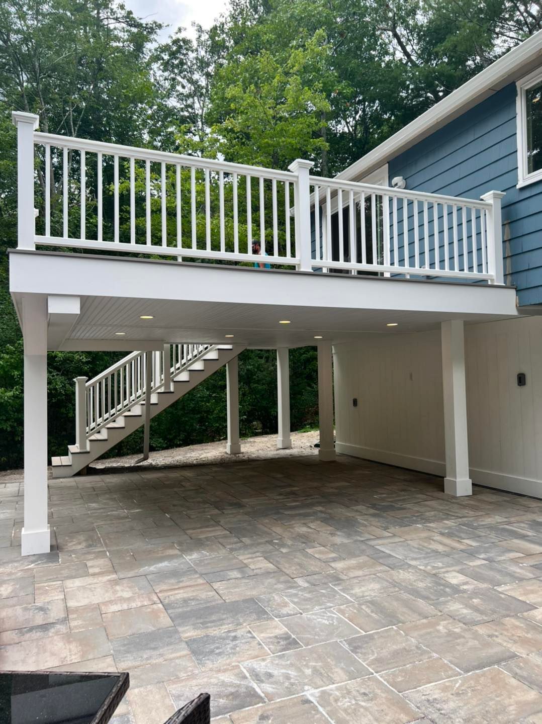 A blue house with a white deck and stairs underneath it