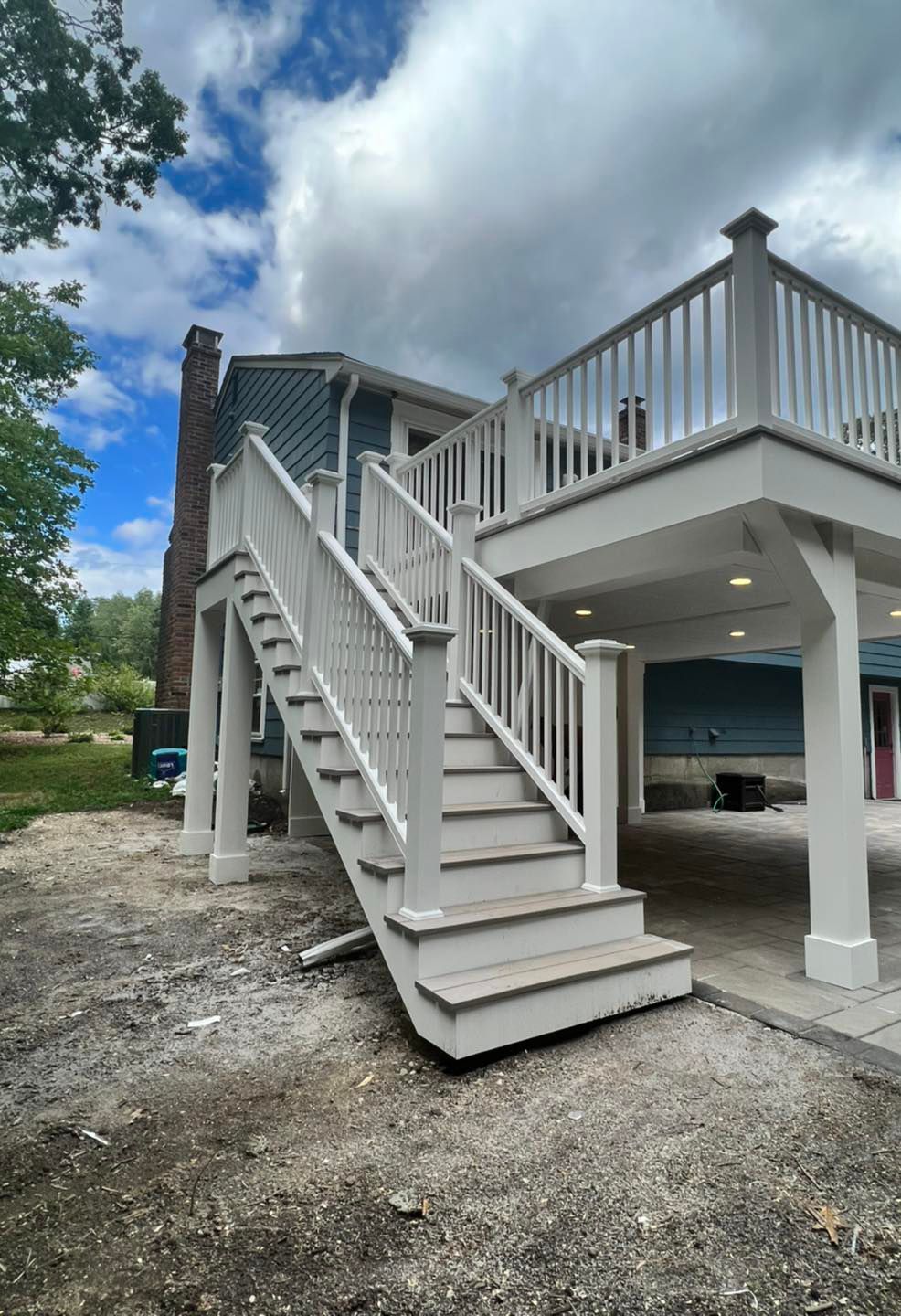 A white deck with stairs leading up to it in front of a house