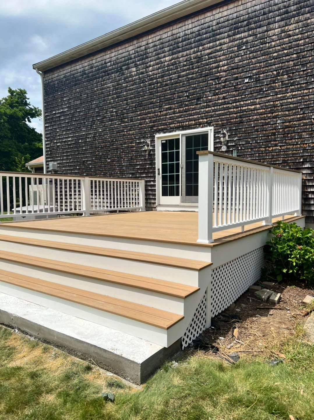 A wooden deck with stairs and a white railing is in front of a house