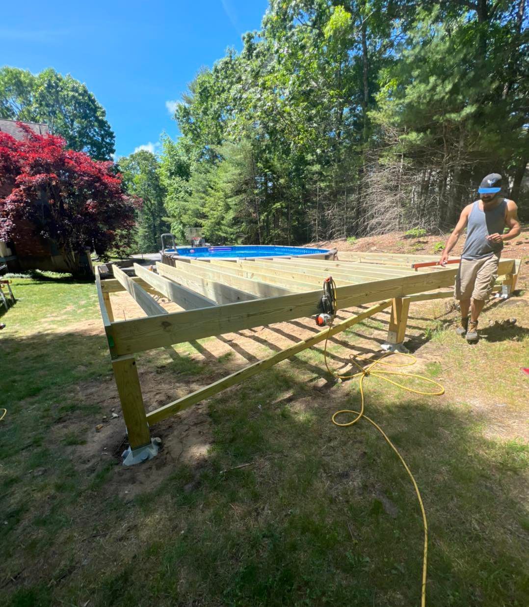 A man is working on a wooden deck in a backyard