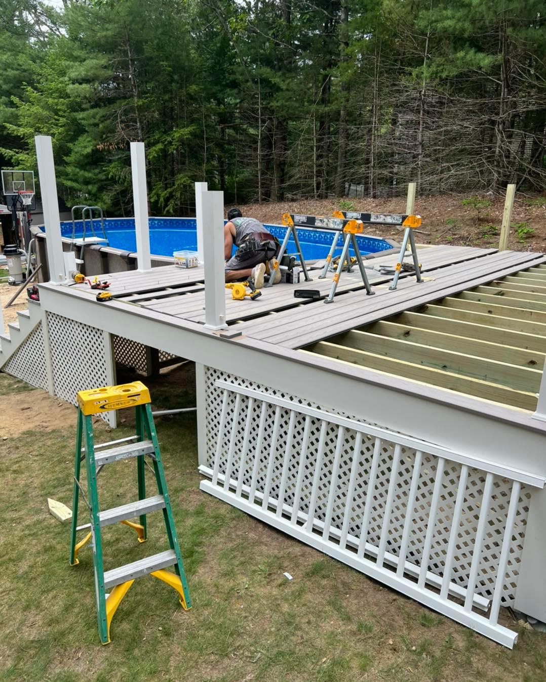 A man is working on a deck next to a pool
