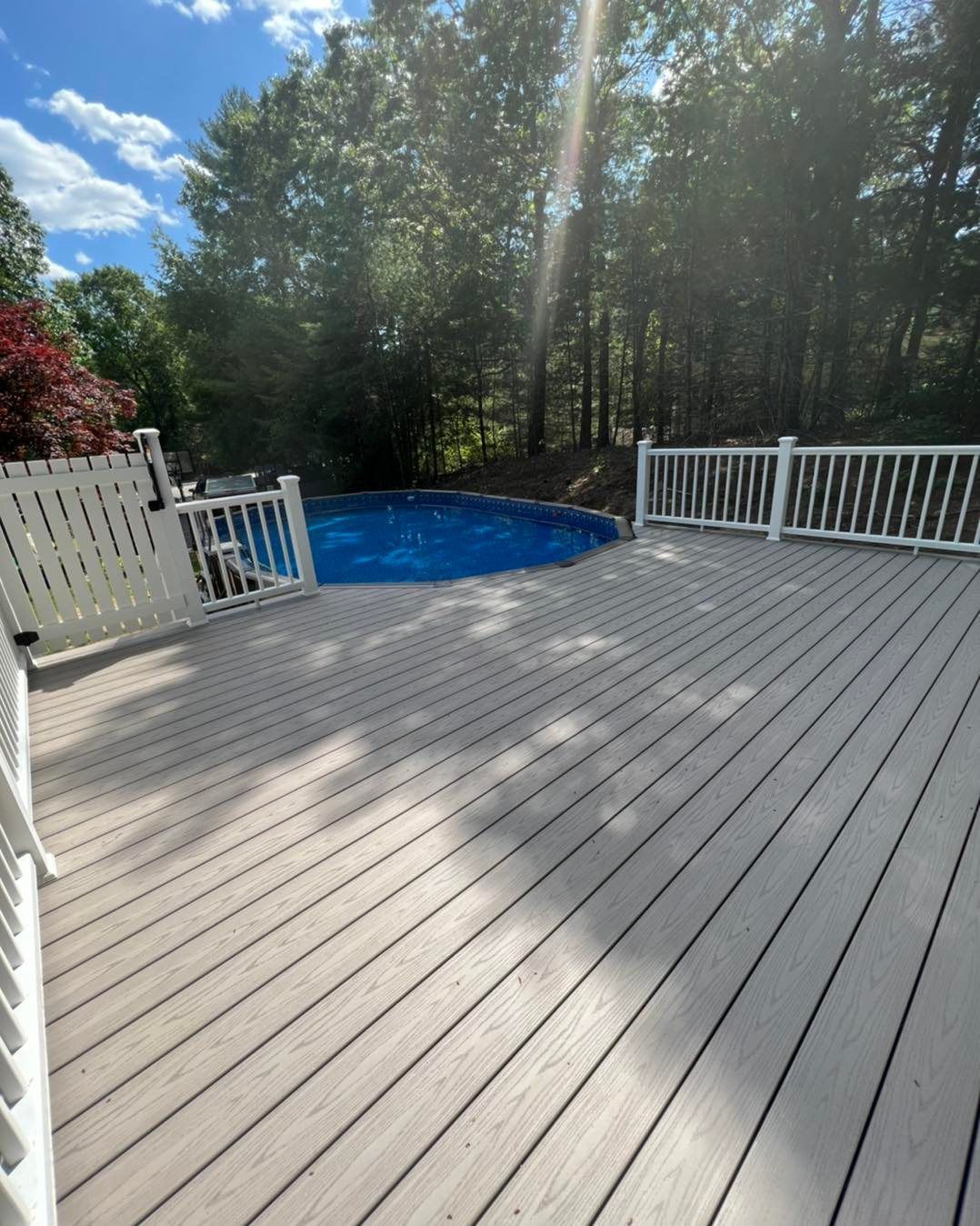 A large deck with a pool in the background