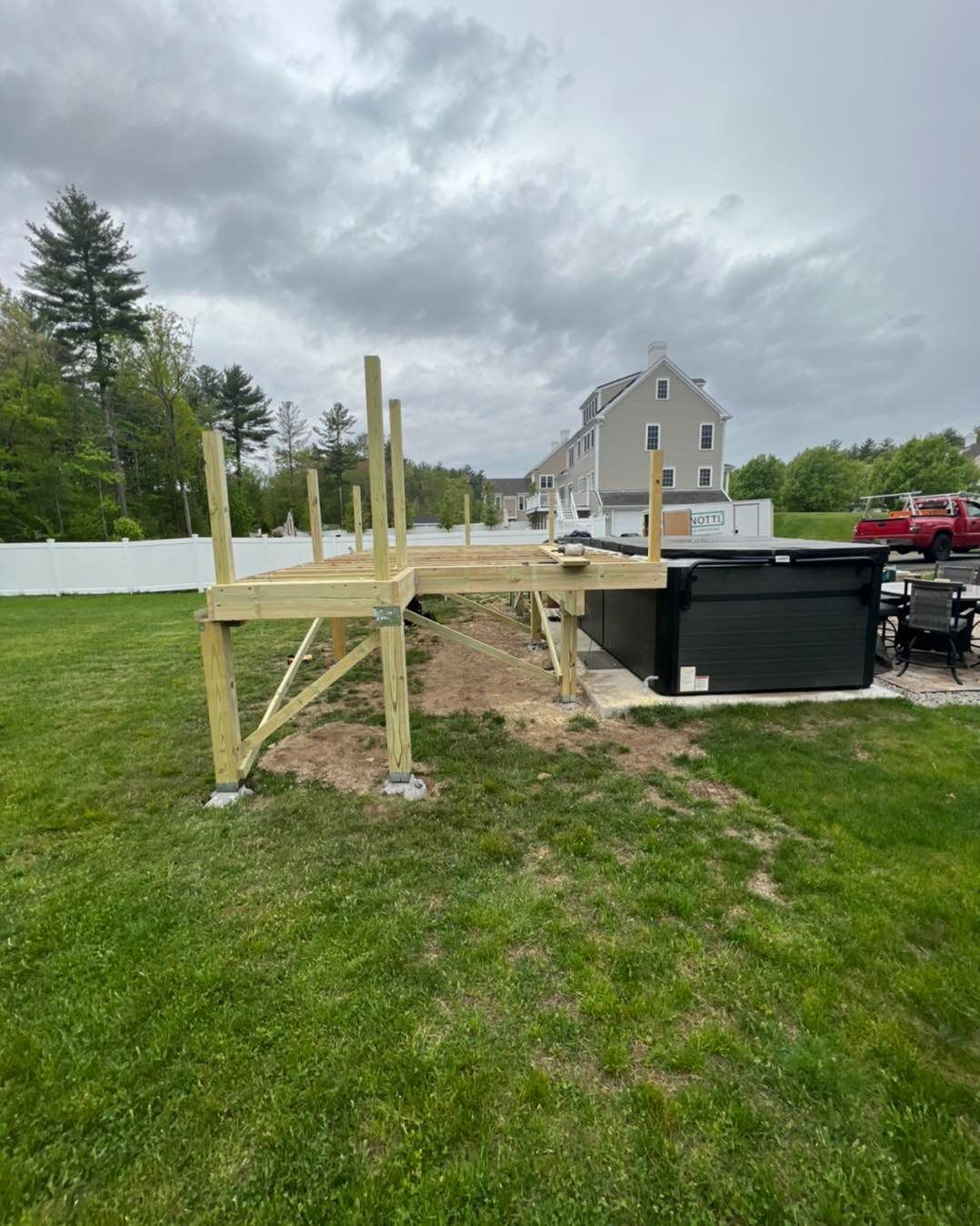A wooden deck is being built in the backyard of a house