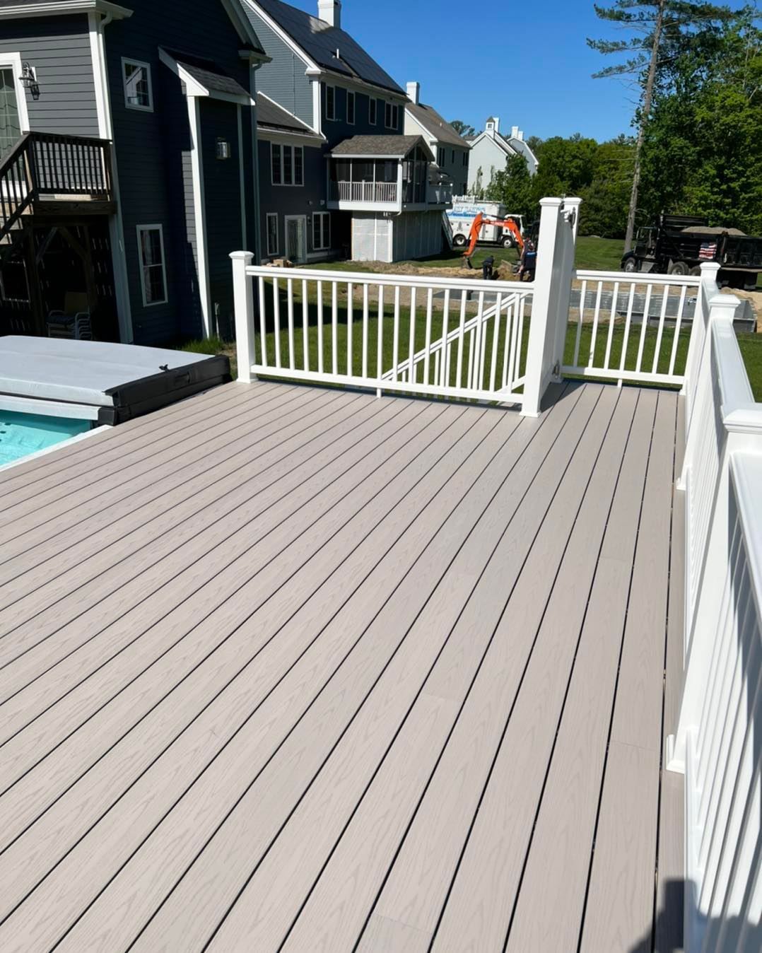 A deck with a white railing and a pool in the background