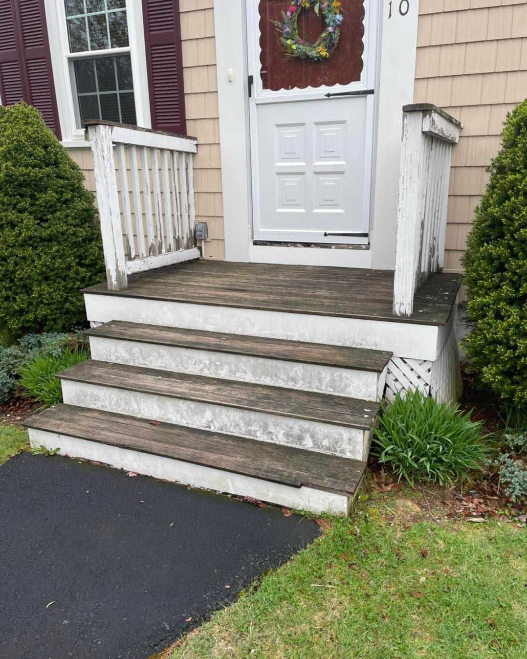 A wooden porch with stairs leading up to the front door of a house