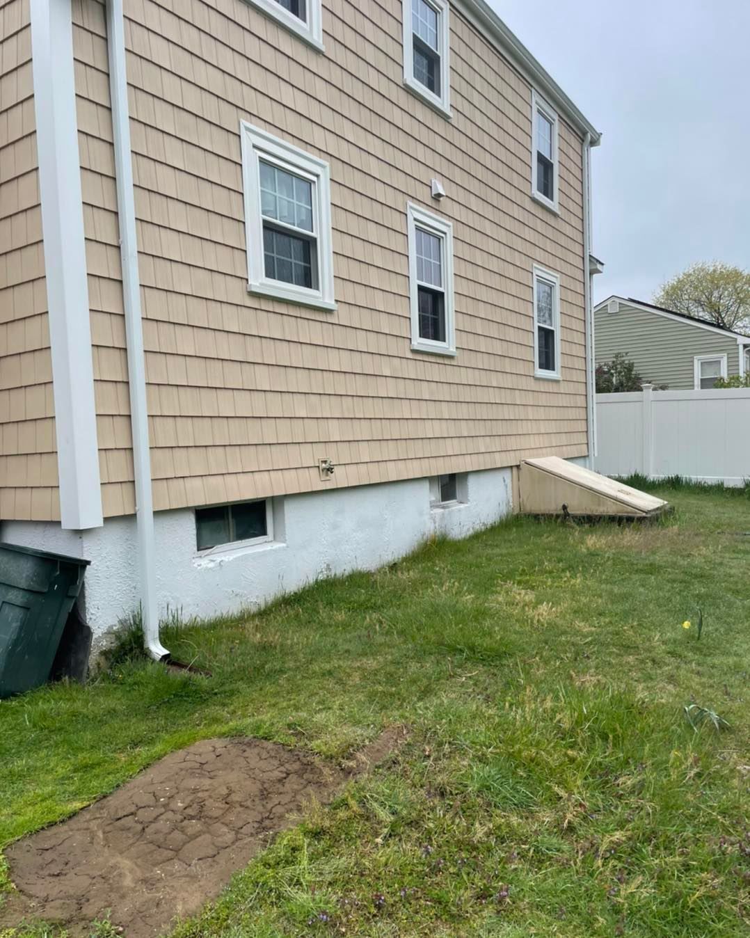 A large house with a lot of windows is sitting on top of a lush green field