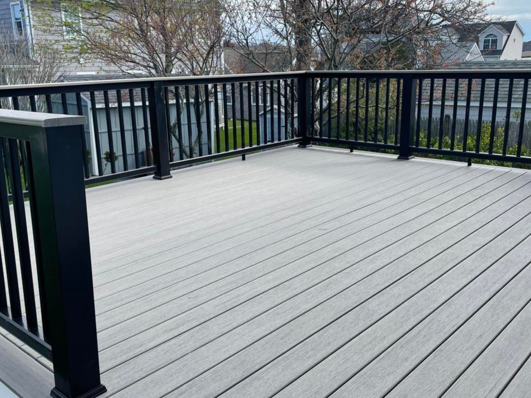 A composite deck with a black railing and a view of a house