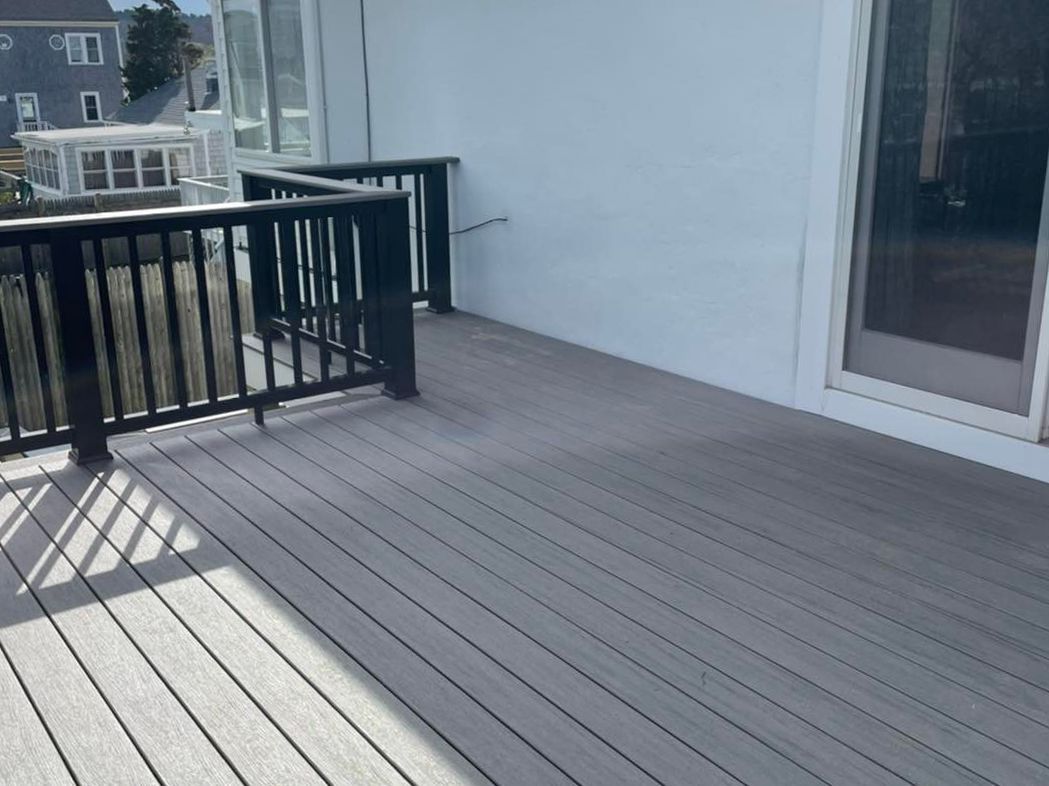 A deck with a black railing and a sliding glass door